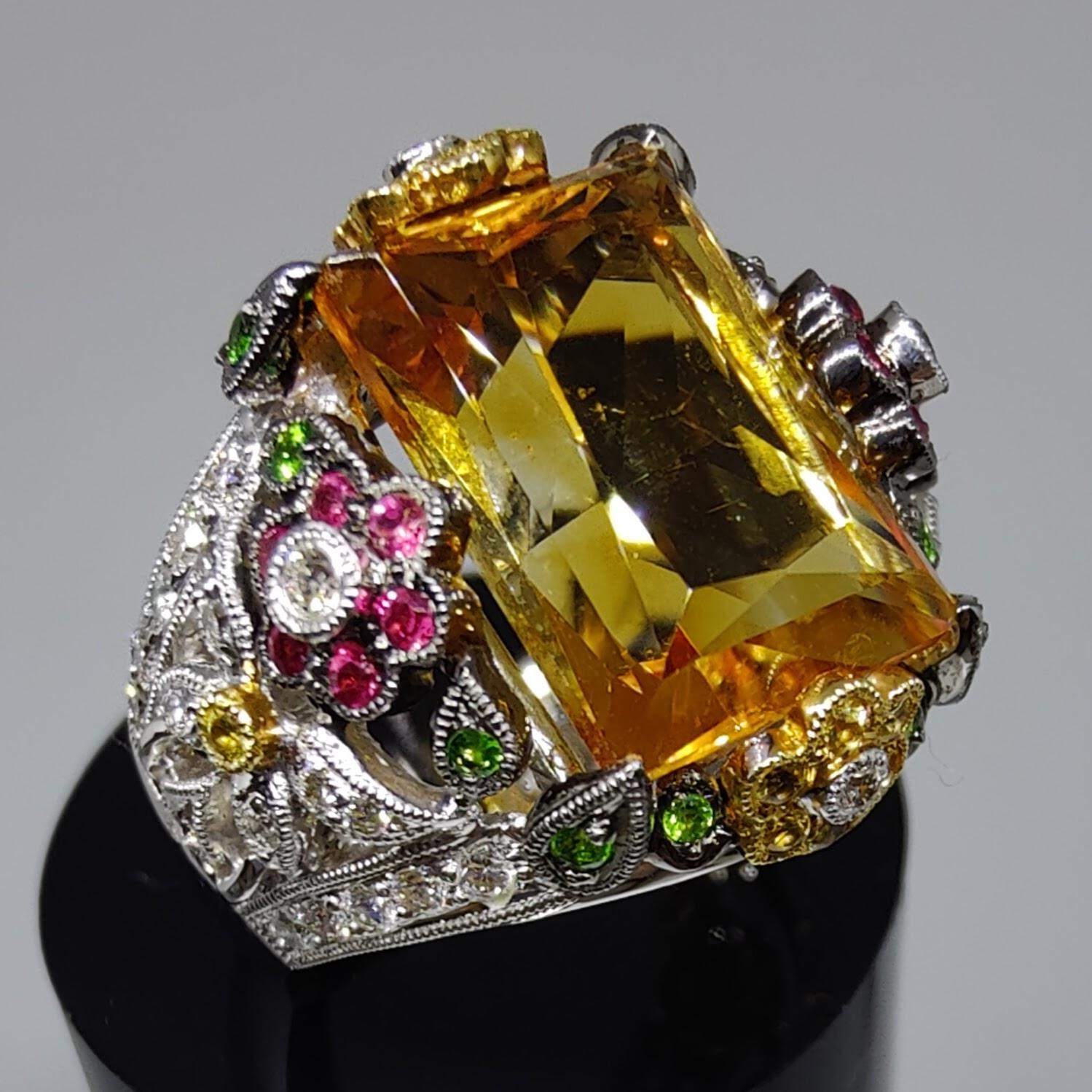 This stunning cocktail ring is sure to turn heads with its baroque style and sparkling gemstones. The centerpiece of the ring is a beautiful 11.35 carat topaz, surrounded by ruby and yellow sapphire flowers and green emerald leaves. The ring is