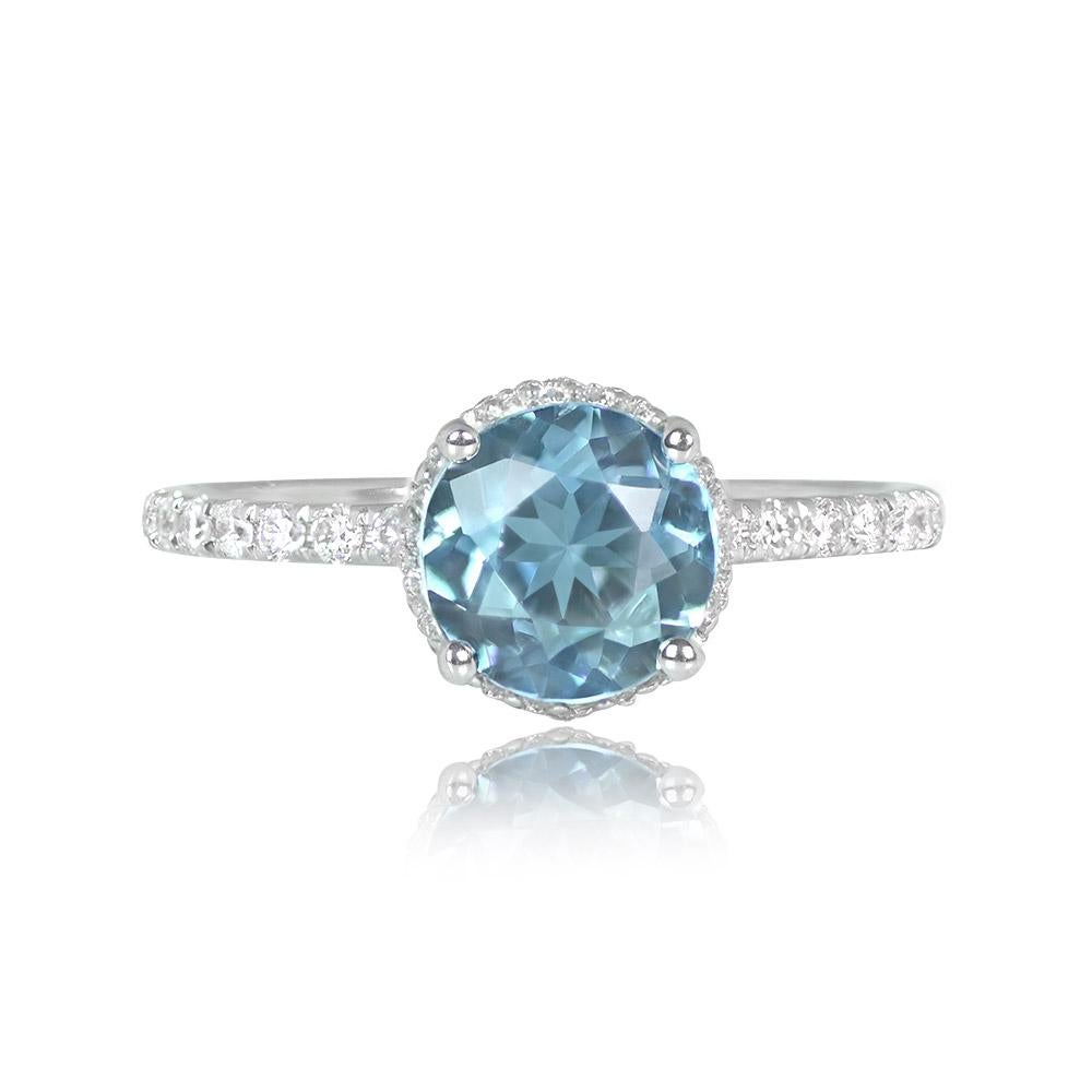This elegant ring showcases a 1.13-carat round aquamarine in a prong setting, complemented by round brilliant cut diamonds along the shoulders and under-gallery. The total diamond weight is around 0.38 carats. It's meticulously handcrafted in 18k