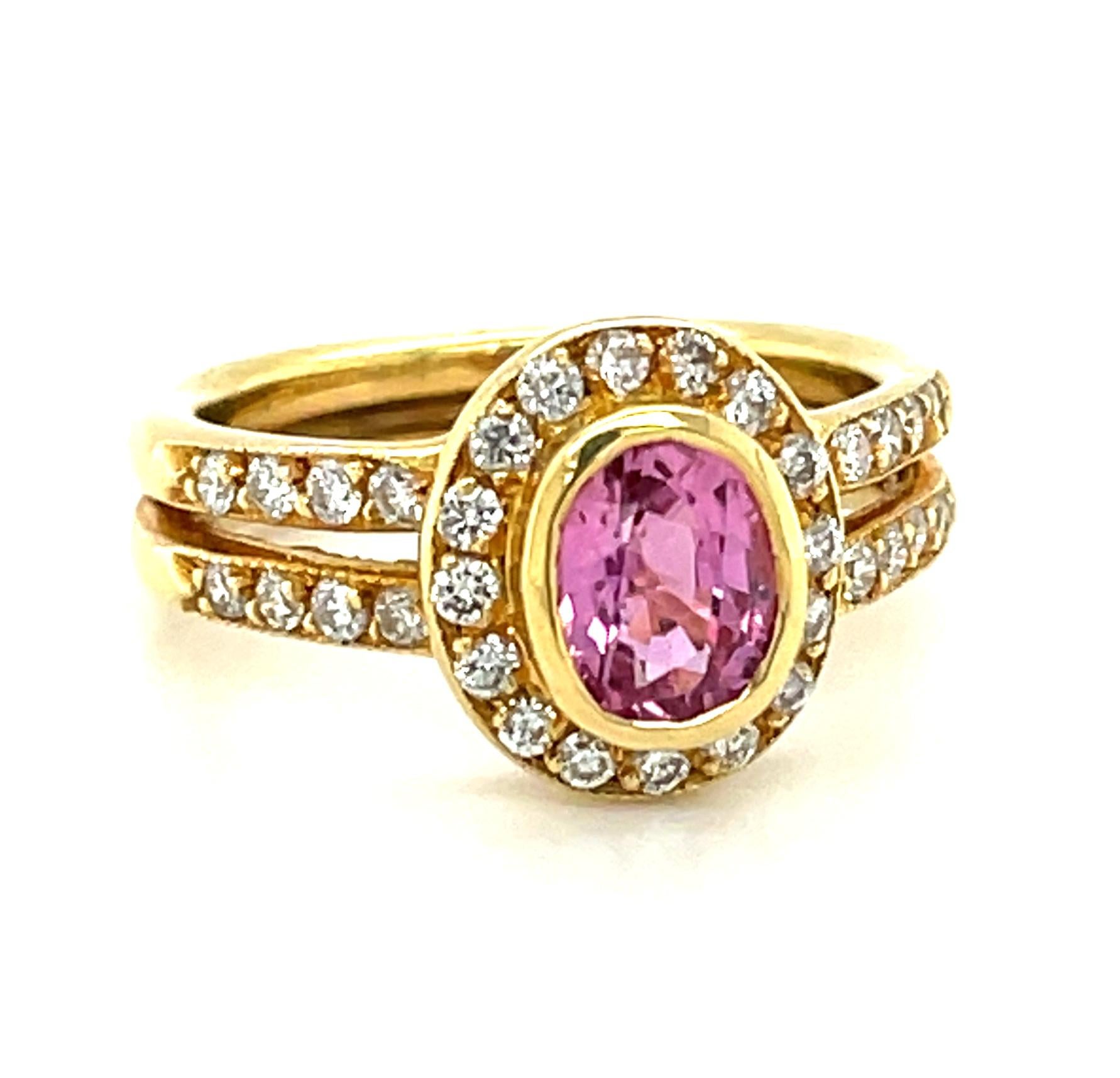 This pretty ring features a vibrant pink sapphire and sparkling diamonds in an 18k yellow gold setting that is perfect for everyday wear! The pink sapphire has been bezel set and framed with a halo of white diamonds, with two rows of additional