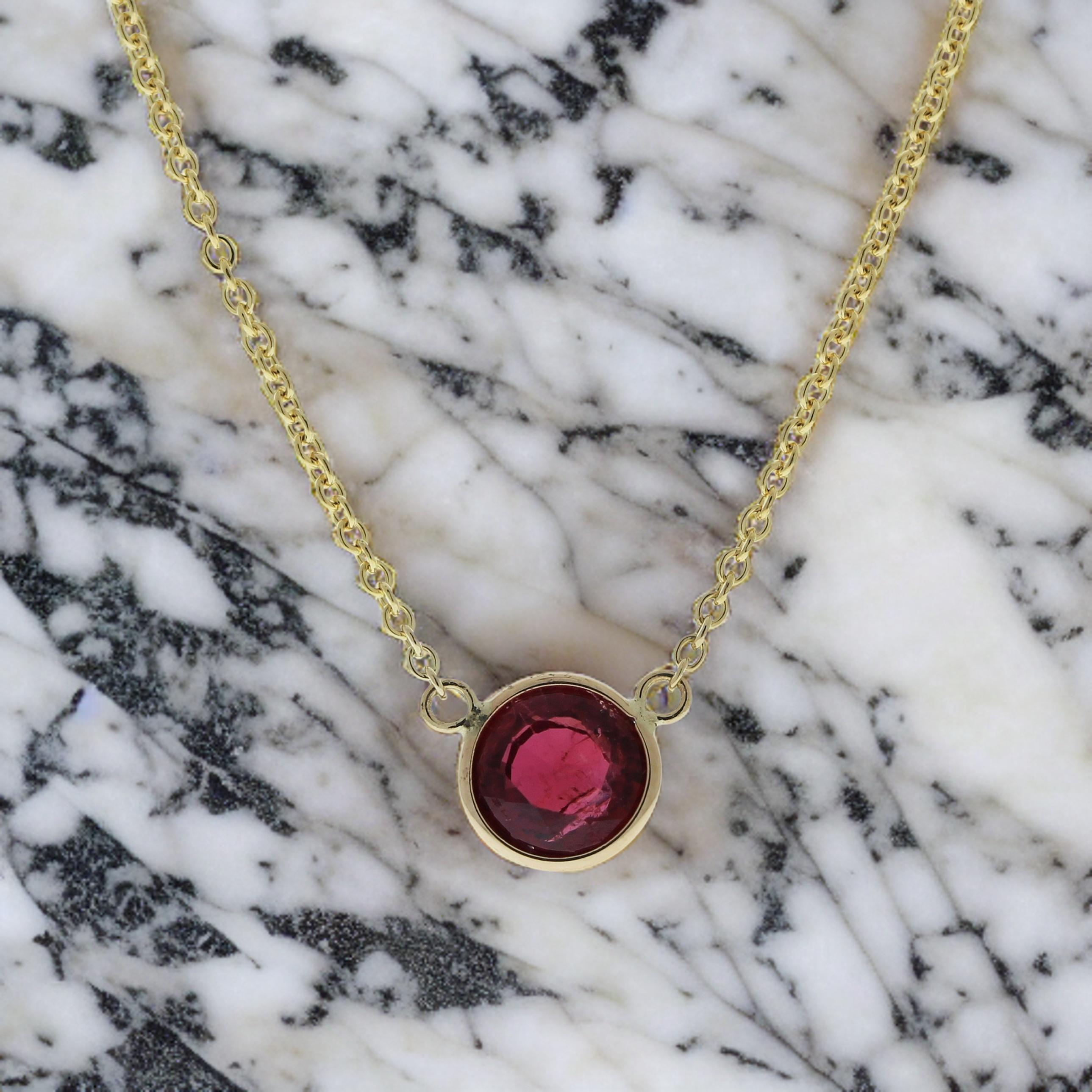The necklace features a 1.14-carat round-cut ruby set in a 14 karat yellow gold pendant or setting. The round cut and the rich red color of the ruby against the yellow gold setting are likely to create an elegant and eye-catching fashion piece,