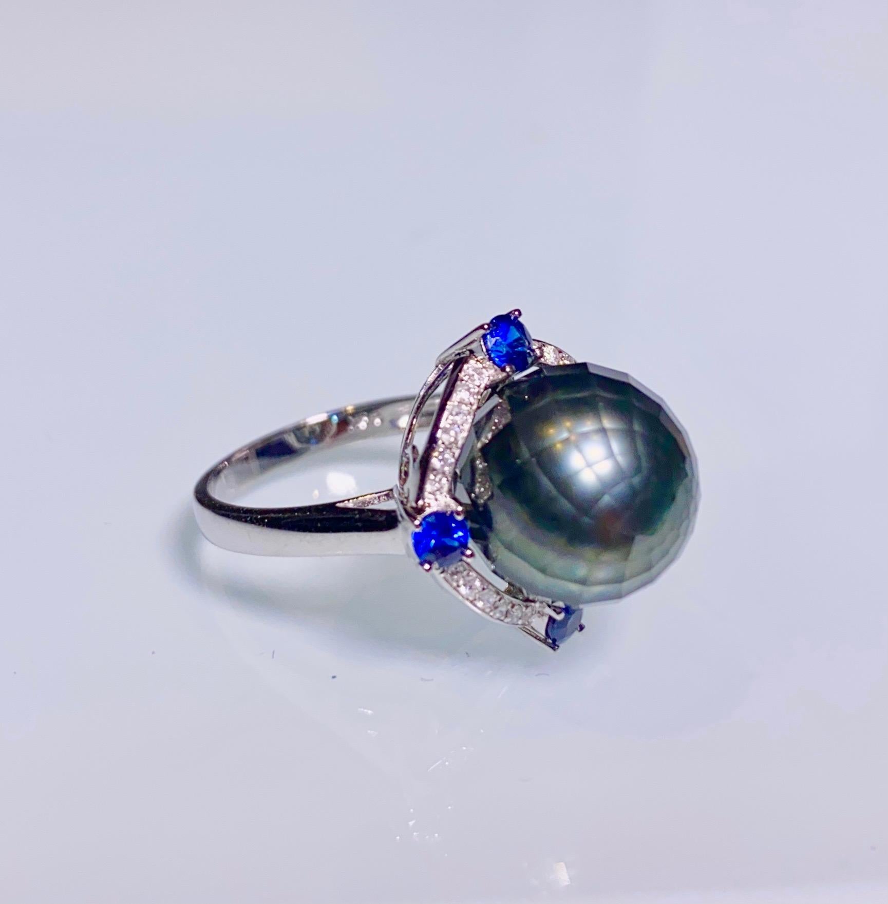 Ein 11,4 mm facettierter Ring aus schwarzer Tahiti-Perle, blauem Saphir und Diamant in 18k Weißgold
Es bestand aus einer runden, facettierten Tahiti-Perle
Blauer Saphir
Natürlicher Diamant 

US RIng Größe ist 6 1/2, der Innendurchmesser des Ringes