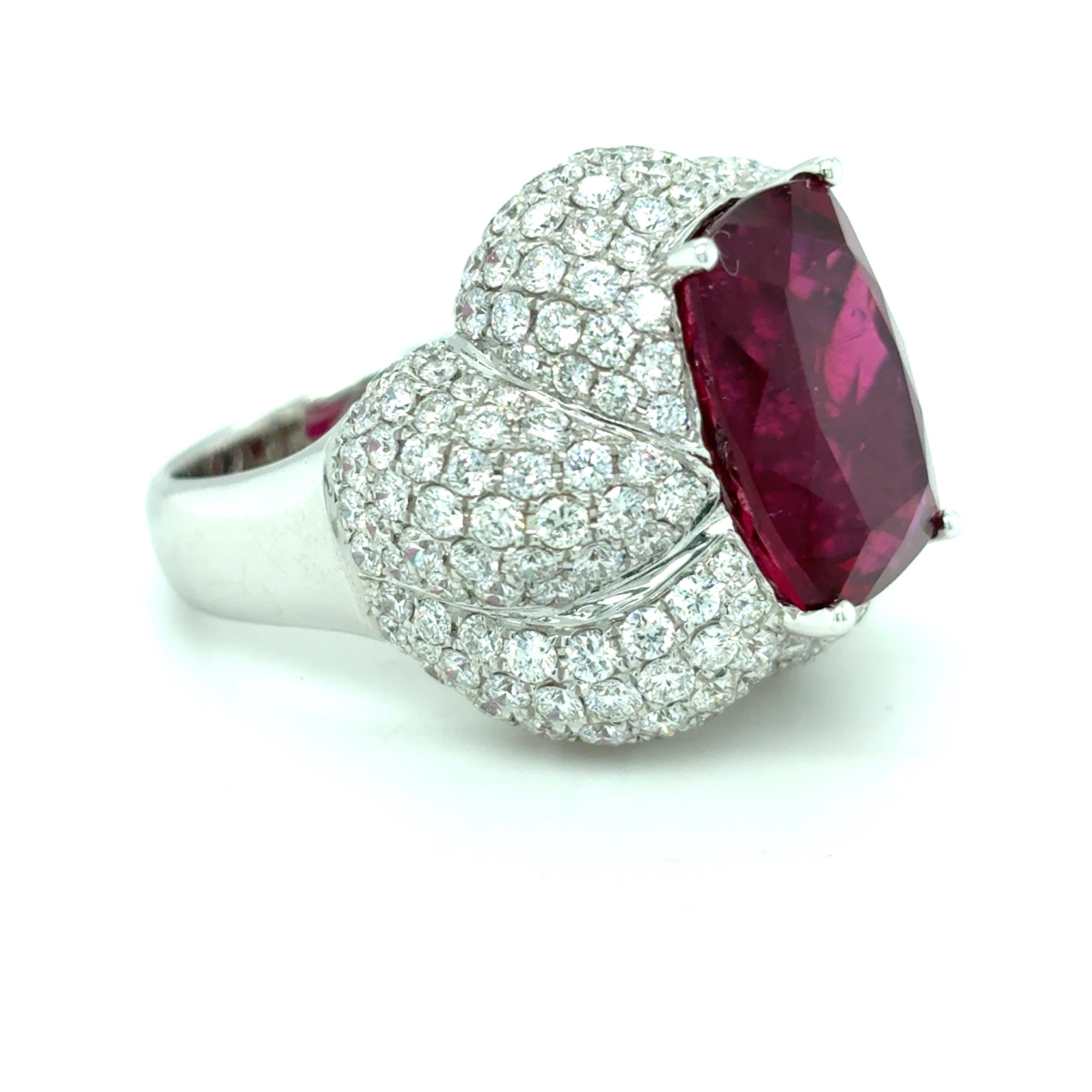 Une tourmaline rubellite de 11,41 carats, taillée en coussin et d'une teinte rose-rouge éclatante, occupe le devant de la scène dans cette bague extraordinaire. La pierre précieuse est entourée d'un pavage floral complexe de diamants, rehaussé de