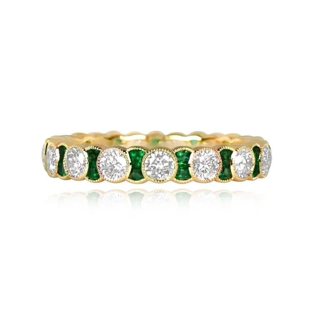 A stunning eternity band crafted in 18k yellow gold, featuring round brilliant-cut diamonds and caliber green emeralds bezel-set with fine milgrain detailing. The band has a total diamond weight of approximately 1.14 carats and a total emerald