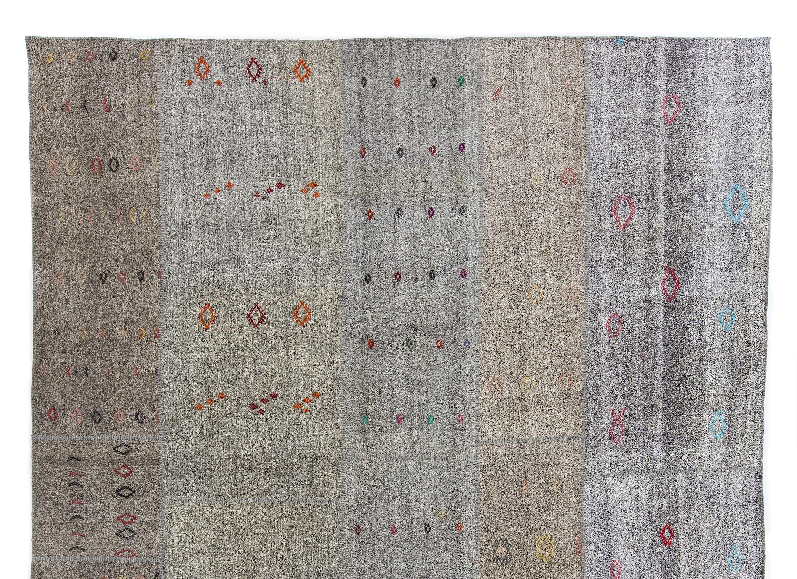 An elegant vintage handwoven Turkish Kilim (flat-weave) with a neutral palette of warm grays and browns including khaki, light fawn and taupe. It is a banded Kilim with colorful fertility motifs on every individually hand sewn piece, handwoven from