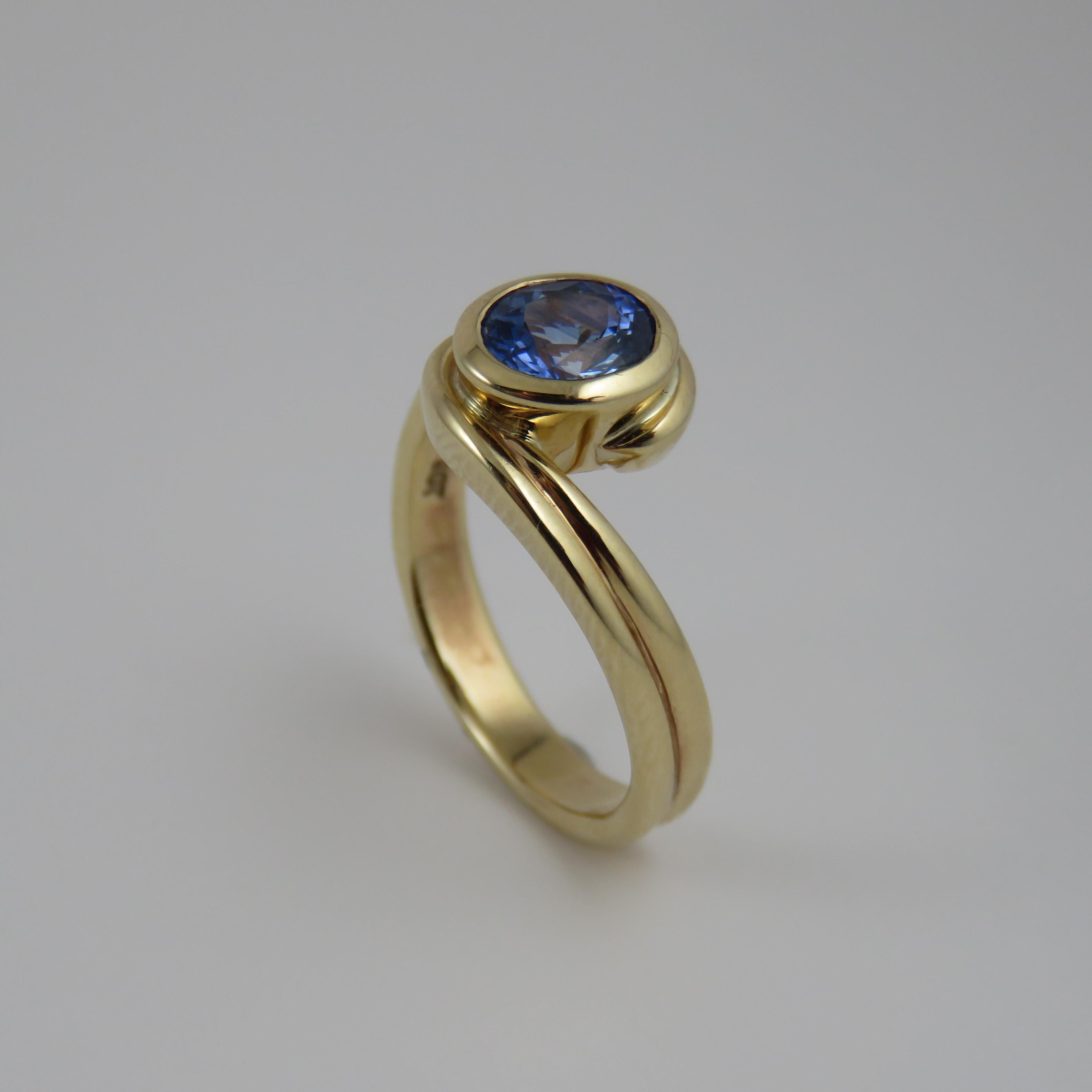 This superb handmade 9k yellow gold sapphire ring is both durable and visually appealing. Its bypass style gives it a distinctive and elegant look, while the oval-shaped blue sapphire stone serves as its centerpiece. The stone is securely held in