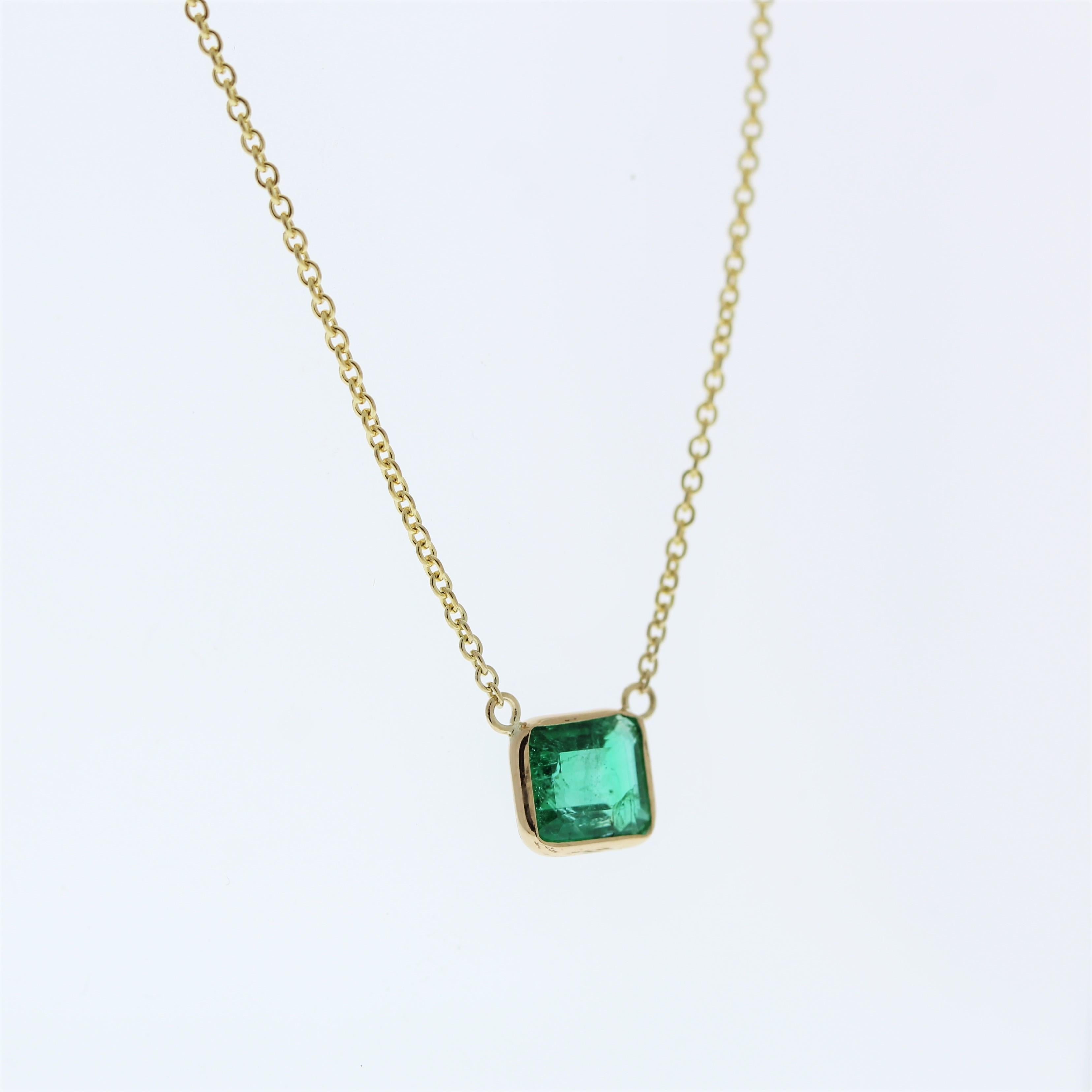 The necklace features a 1.15-carat emerald-cut bluish green emerald set in a 14 karat yellow gold pendant or setting. The combination of the emerald's unique cut and its bluish green color against the yellow gold setting is likely to create a