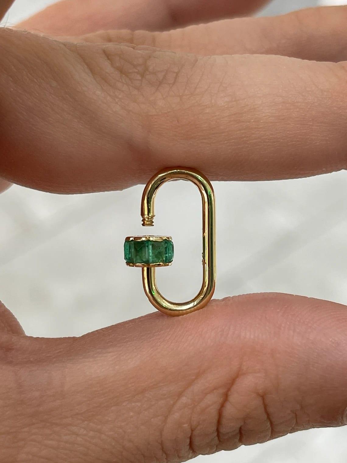 This versatile emerald carabiner showcases a sleek paperclip-inspired design, adorned with a combination of rose-cut and emerald-cut emeralds, elegantly channel-set to highlight their natural beauty. Designed with a secure snap-lock mechanism, this