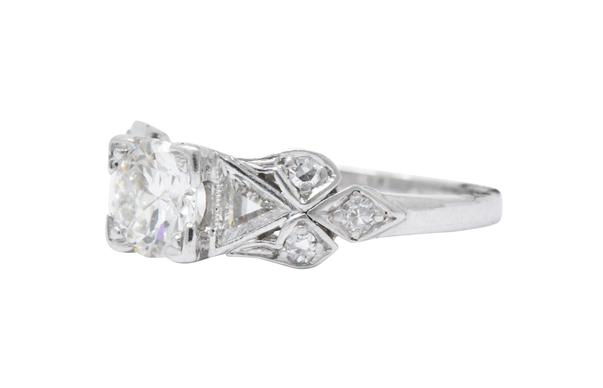 This is an Art Deco platinum and diamond engagement ring. The stunning filigree platinum mounting is circa 1935. The center old European cut diamond weighs approximately 0.73 carat, H color and SI1 clarity. Accenting the center stone are two