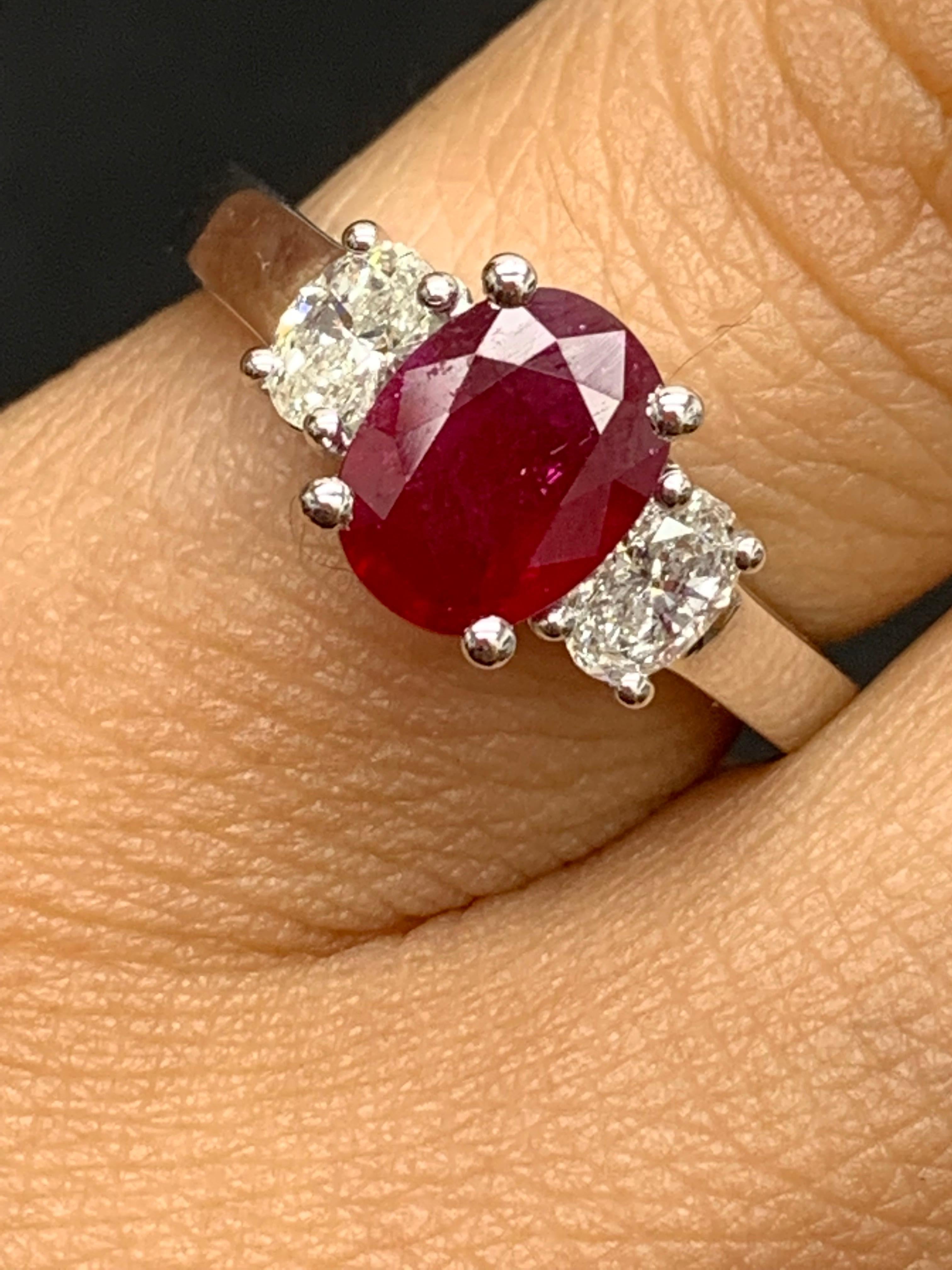 Showcases an Oval cut, Vibrant color lush red Ruby weighing 1.15 carats, flanked by two brilliant oval cut diamonds weighing 0.48 carats. Elegantly set in 18k White Gold.