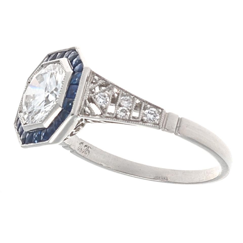 Blue being the color of eternity this is the perfect way to express your infinite love. Featuring a lively 1.15 carat round brilliant cut diamond that is F color, VS1 clarity. Accentuated by a halo of navy blue calibrated sapphires. Crafted in