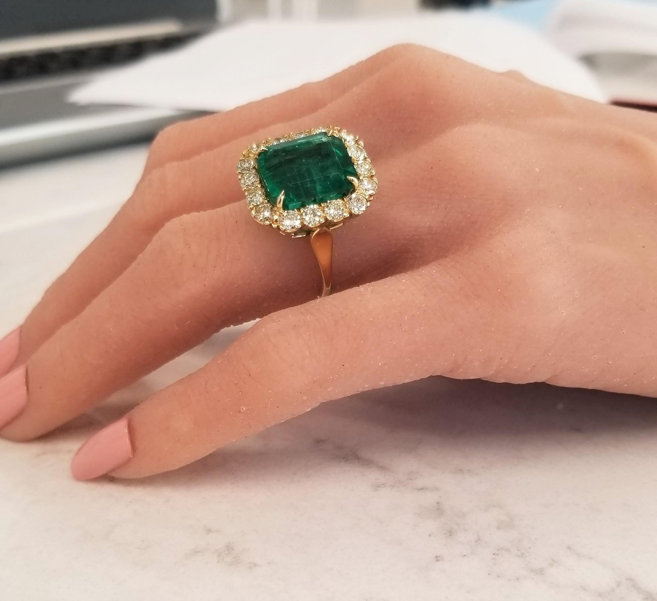 This is an incomparable emerald and diamond ring. This stunning example showcases a 11.53 carat emerald cut Emerald; it exhibits excellent luster and transparency. It measures 13.57 x 11.93 mm. Framed in an elegant halo of 1.73 carats of fancy light