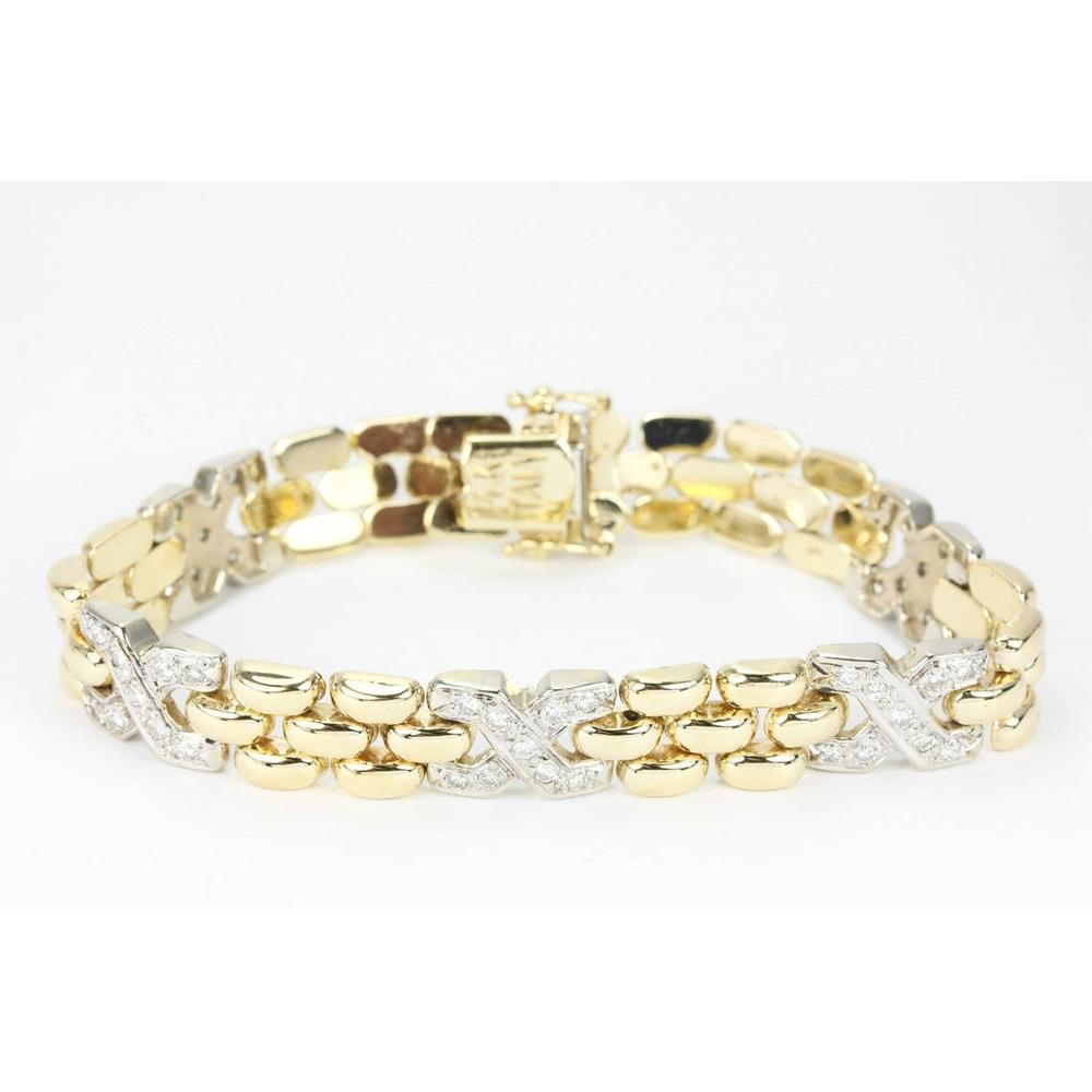 A superb diamond and solid gold bracelet. Handcrafted in glistening 14K yellow gold this bracelet features a unique gold band that is accented with white gold X's that are pave set with diamonds. The diamonds dance under all light settings and weigh