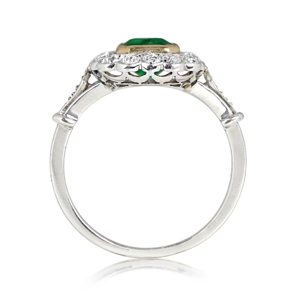 A platinum ring featuring an emerald-cut emerald weighing approximately 1.15 carats, showcasing a deep green color and bezel-set in yellow gold. The emerald is circled by a floral halo of old European diamonds set in half-bezels. Diamond-shaped