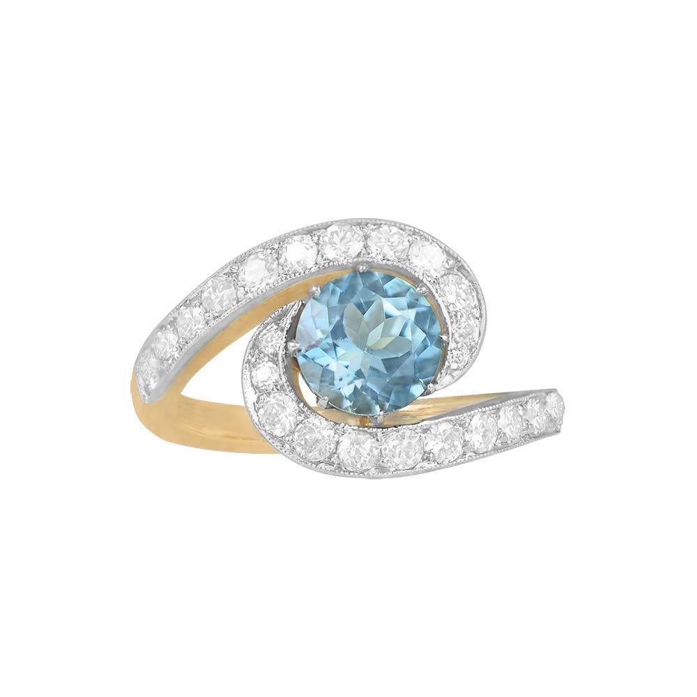 This distinctive engagement ring showcases a 1.15-carat Santa Maria color aquamarine, round-cut and elegantly set in prongs. Along the shoulders, micro-pave-set old European cut diamonds adorn an Edwardian-style swirl design, adding to its vintage