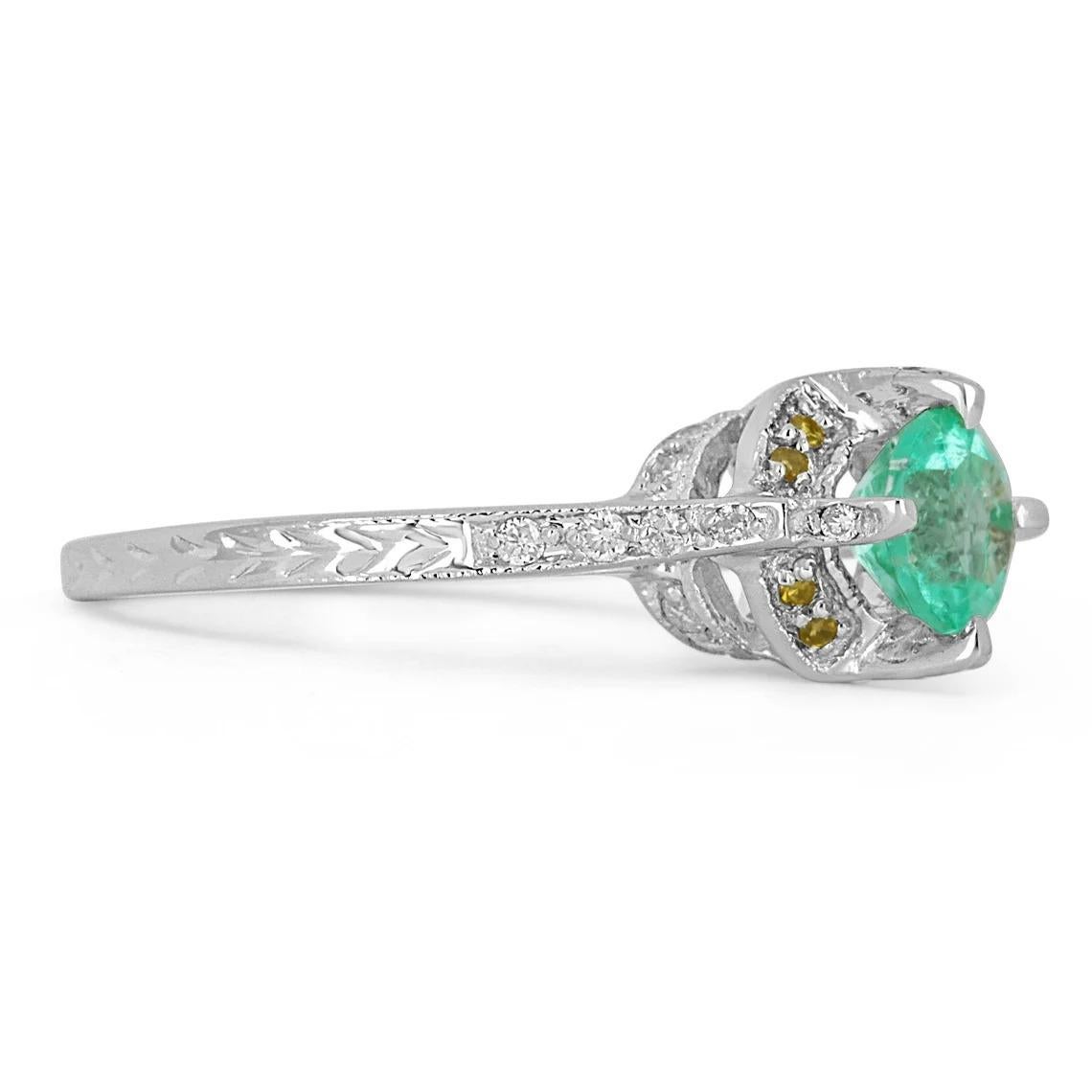 Featured is a stunning Colombian emerald and diamond engagement ring. The center of attention is a beautiful, and petite 0.84-carat round Colombian emerald showcasing a vivid, medium-light, green color with excellent luster. 26 brilliant round white