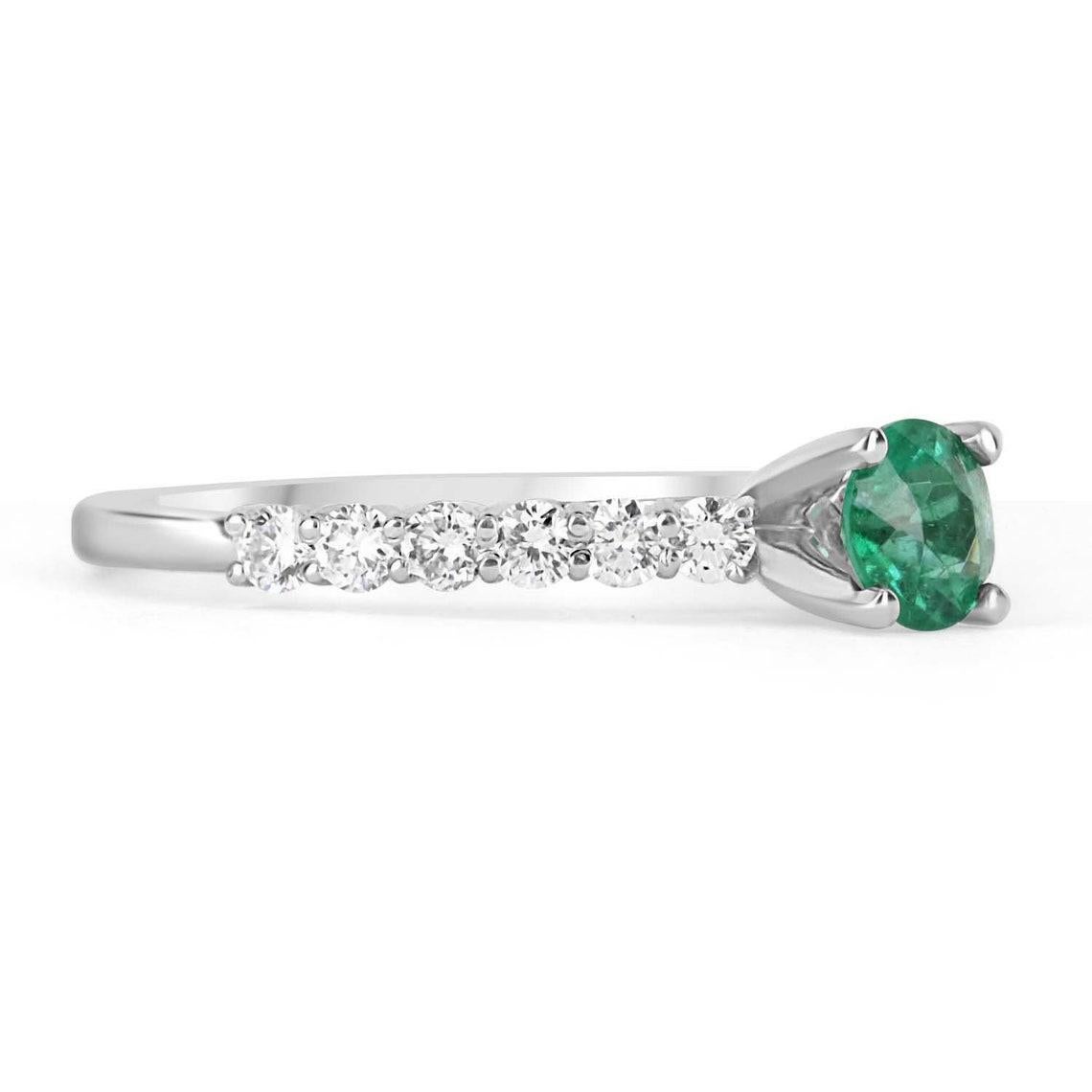 Displayed is a classic 1.15tcw natural emerald & diamond solitaire with accents engagement ring in 14K white gold. This gorgeous solitaire ring carries a full 0.55-carat emerald in a four-prong setting. Fully faceted, this gemstone showcases