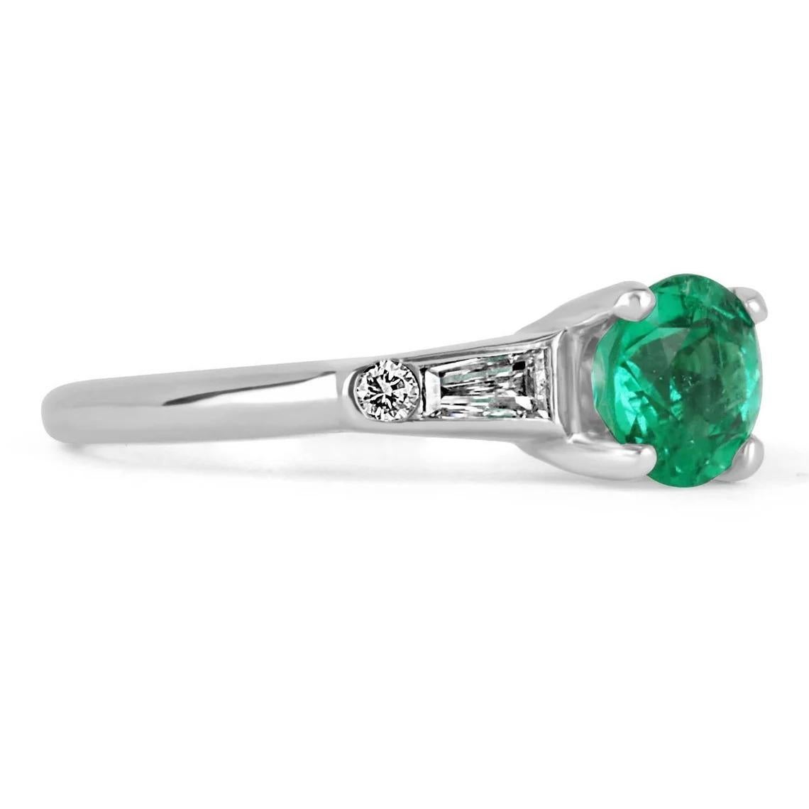 A classic among engagement rings, this emerald, and tapered diamond engagement ring features a vibrant round Colombian emerald. The genuine gemstone has incredible deep bluish-green color and excellent eye clarity. The gem sits gently in a