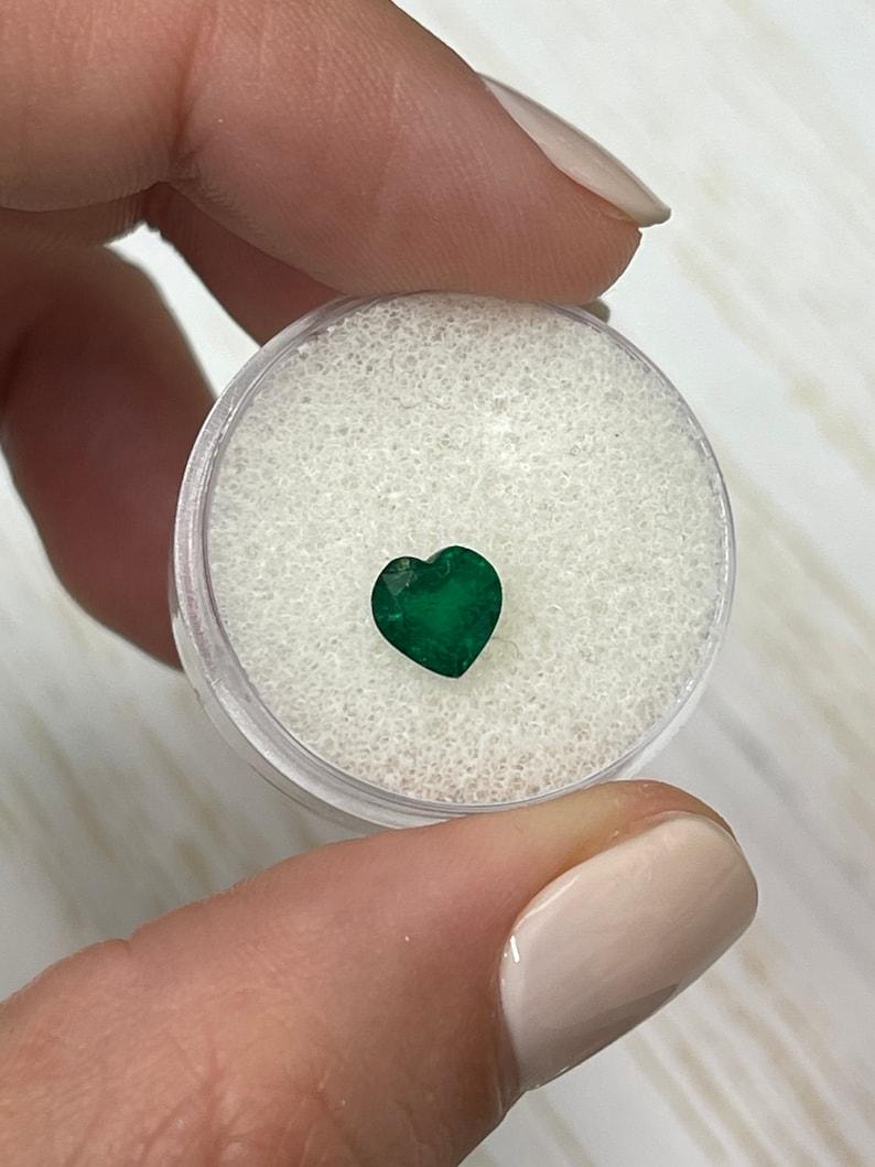 Stone: Emerald
Weight: 1.16-carats
Shape: Heart Cut
Clarity: Semi-Transparent
Luster: Very Good/Good
Color: Dark Green
Measurements: 6.72mm x 6.76mm x 4.54mm
Geographic Origin: Zambia
Treatment: Natural, Oiling

Comments: Due to their growth