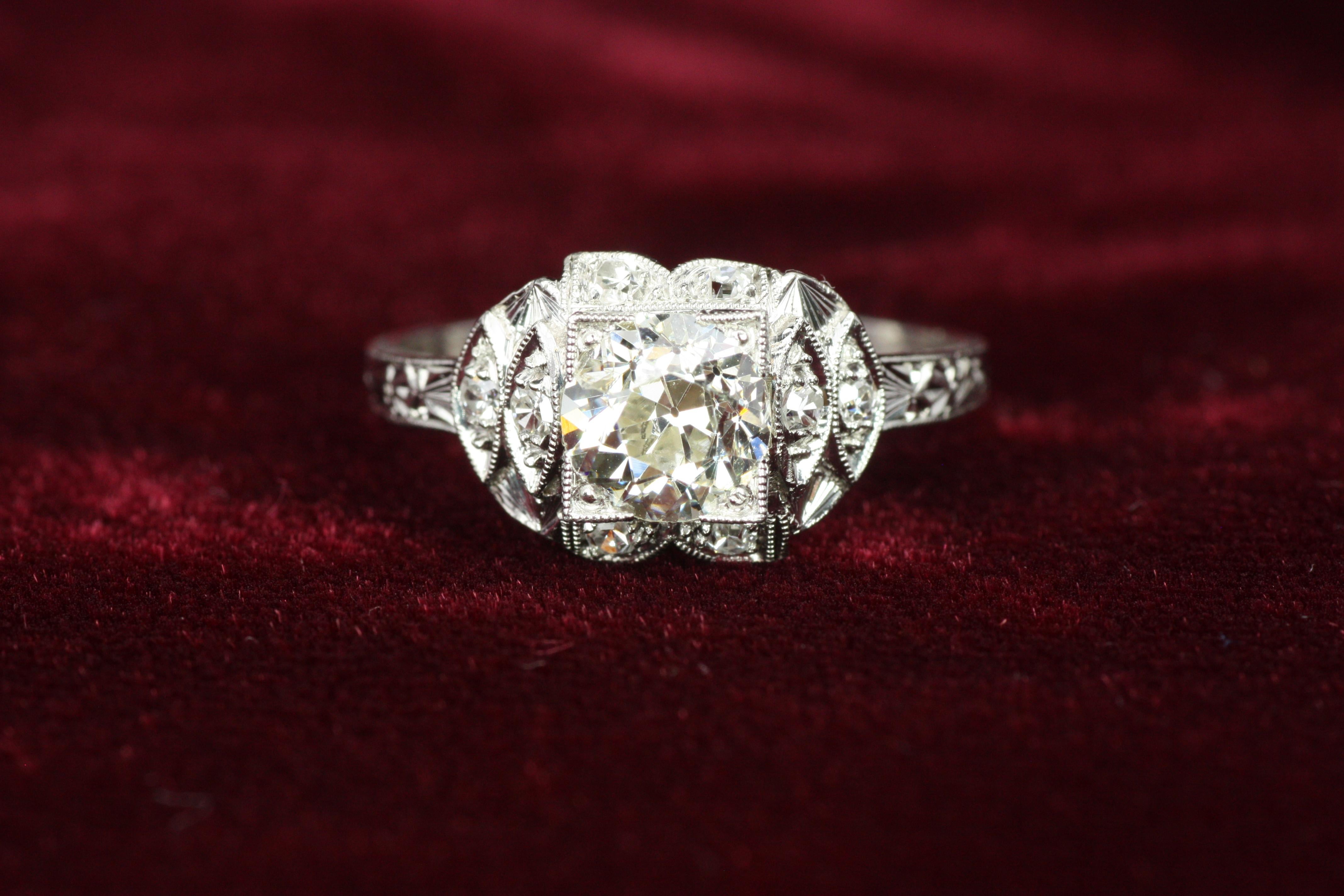 Este audaz y geométrico anillo de compromiso Art Decó de los años 30 presenta un diamante de talla europea antigua de 1,00 ct rodeado de una combinación de diamantes redondos de talla única y talla completa. Engarzado en platino con intrincados