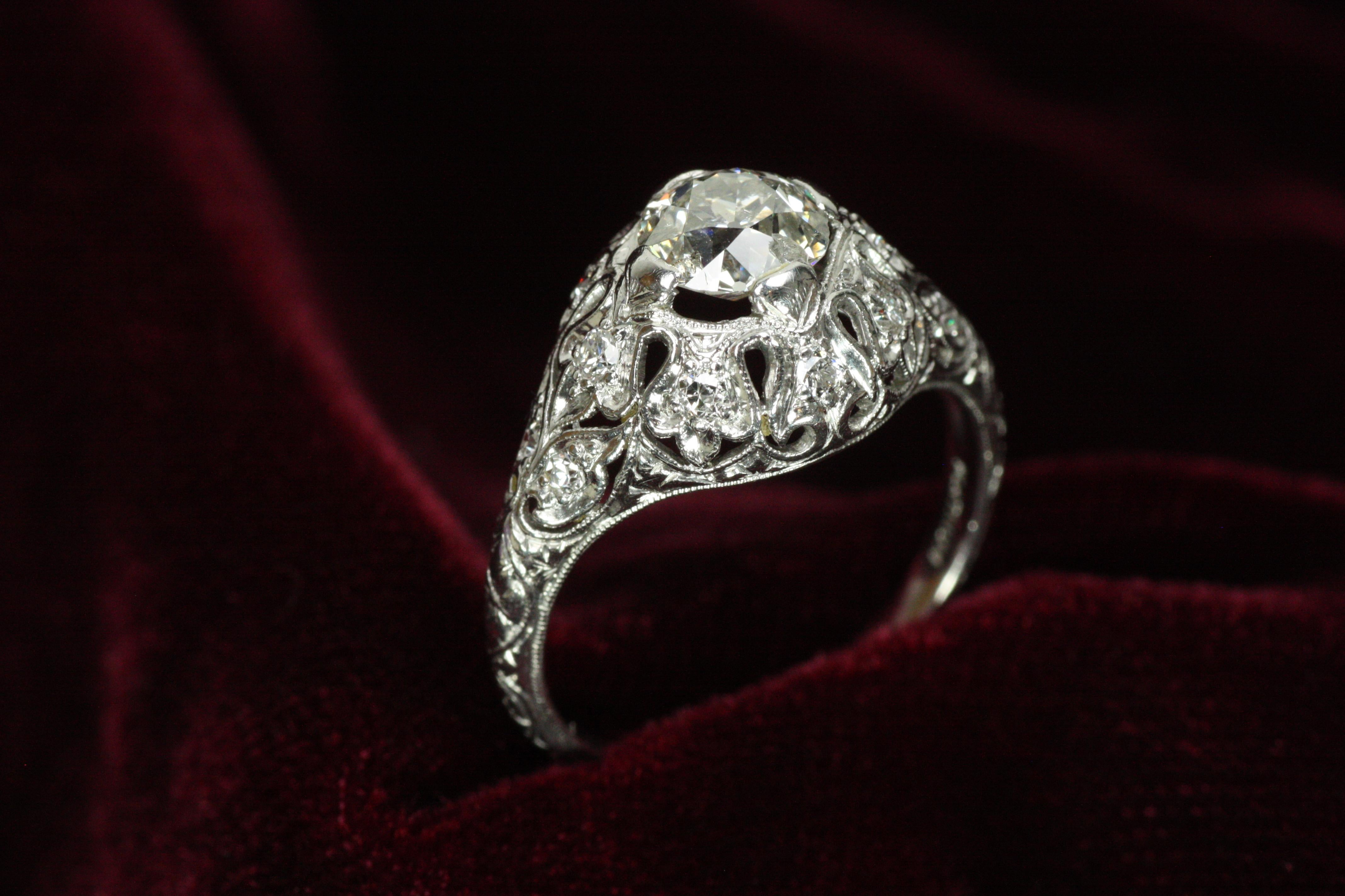 Step back into the elegance of the roaring twenties with this authentic Art Deco antique ring, crafted in platinum. A 0.91ct old European cut diamond sparkles at its heart, framed by intricate filigree and additional round diamonds that add sparkle