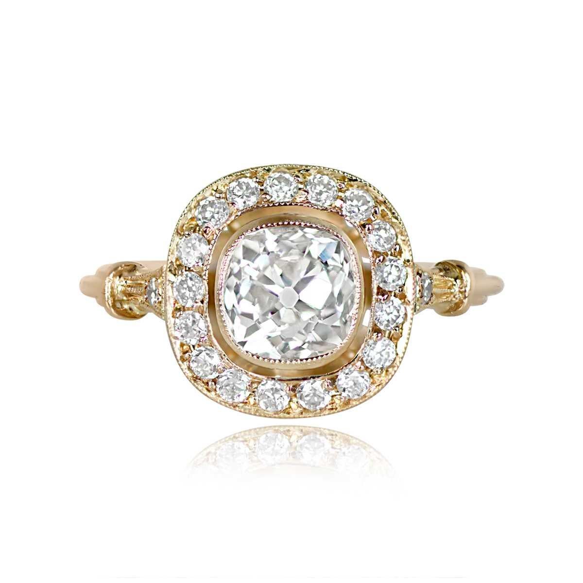 This antique engagement ring showcases a 1.16-carat cushion-cut diamond (J color, VS2 clarity) at its center, encircled by a bezel-set halo of old European cut diamonds. The exquisite design features an 18k yellow gold setting with intricate