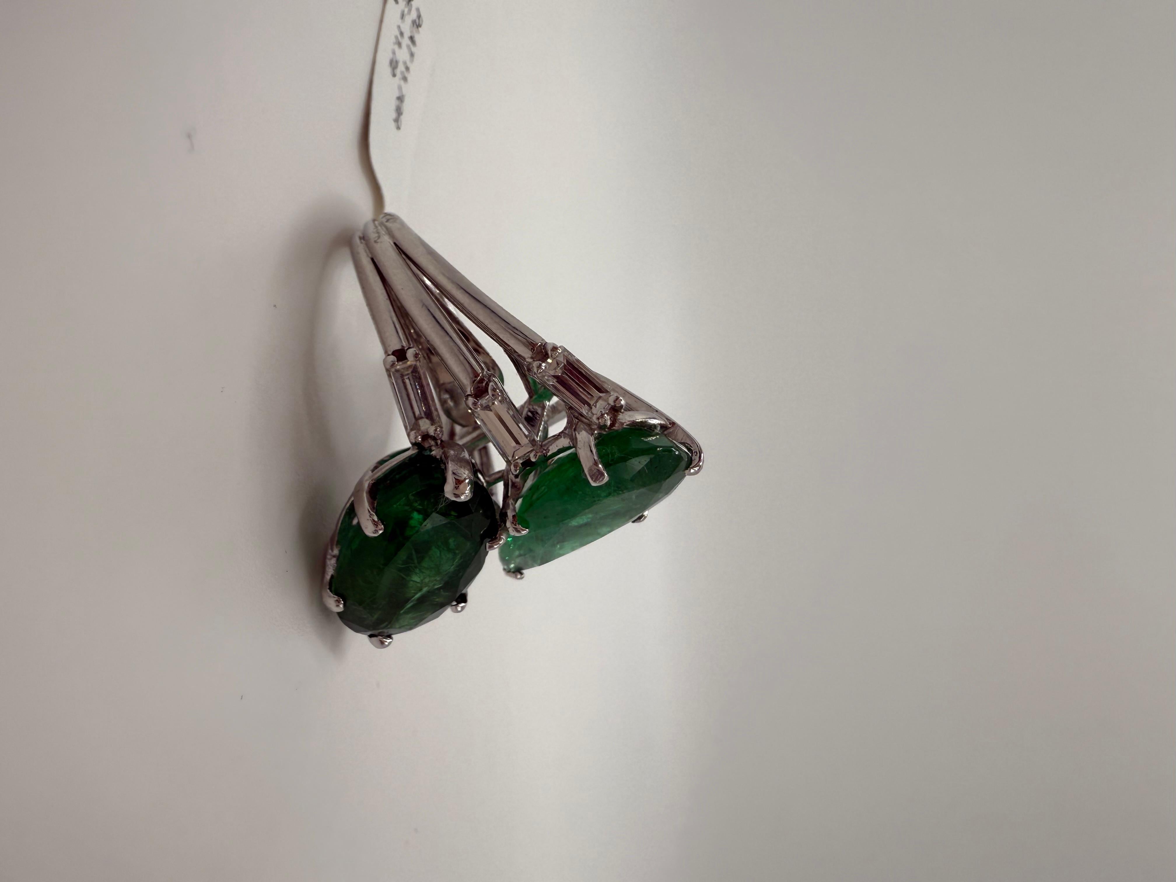 Llamativo en escala y diseño, este excepcional anillo de platino exhibe dos vívidas esmeraldas en forma de pera y oval, con un total de 11,72 quilates, engarzadas una al lado de la otra en un atrevido estilo bypass. Las esmeraldas irradian un