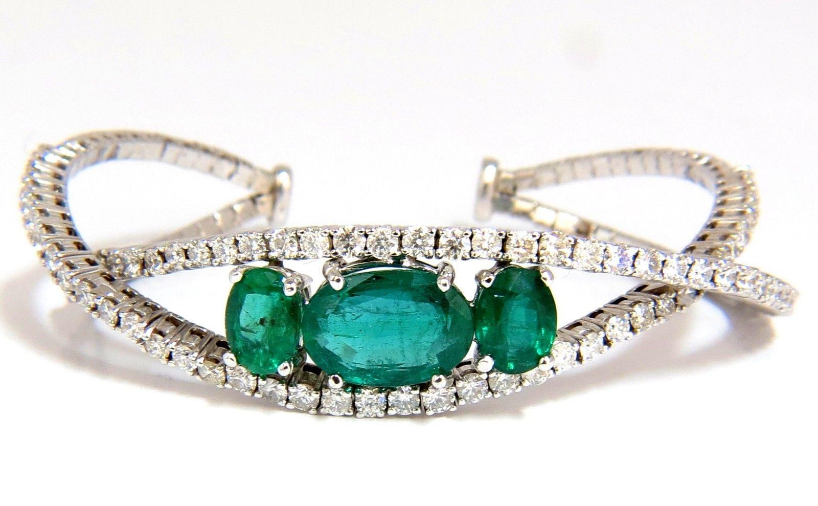 Crossover Bangle Bracelet

8.00ct. Natural Emeralds (3)

Green, Transparent & oval cut.

5.00ct. Center: 12.8 X 8.6mm

3.00ct. (2) Smaller: 7.7 X 5.8mm

3.75ct. diamonds:

Rounds, G color Vs-2 clarity.

14kt. white gold 

21.5 Grams.

.56 inch