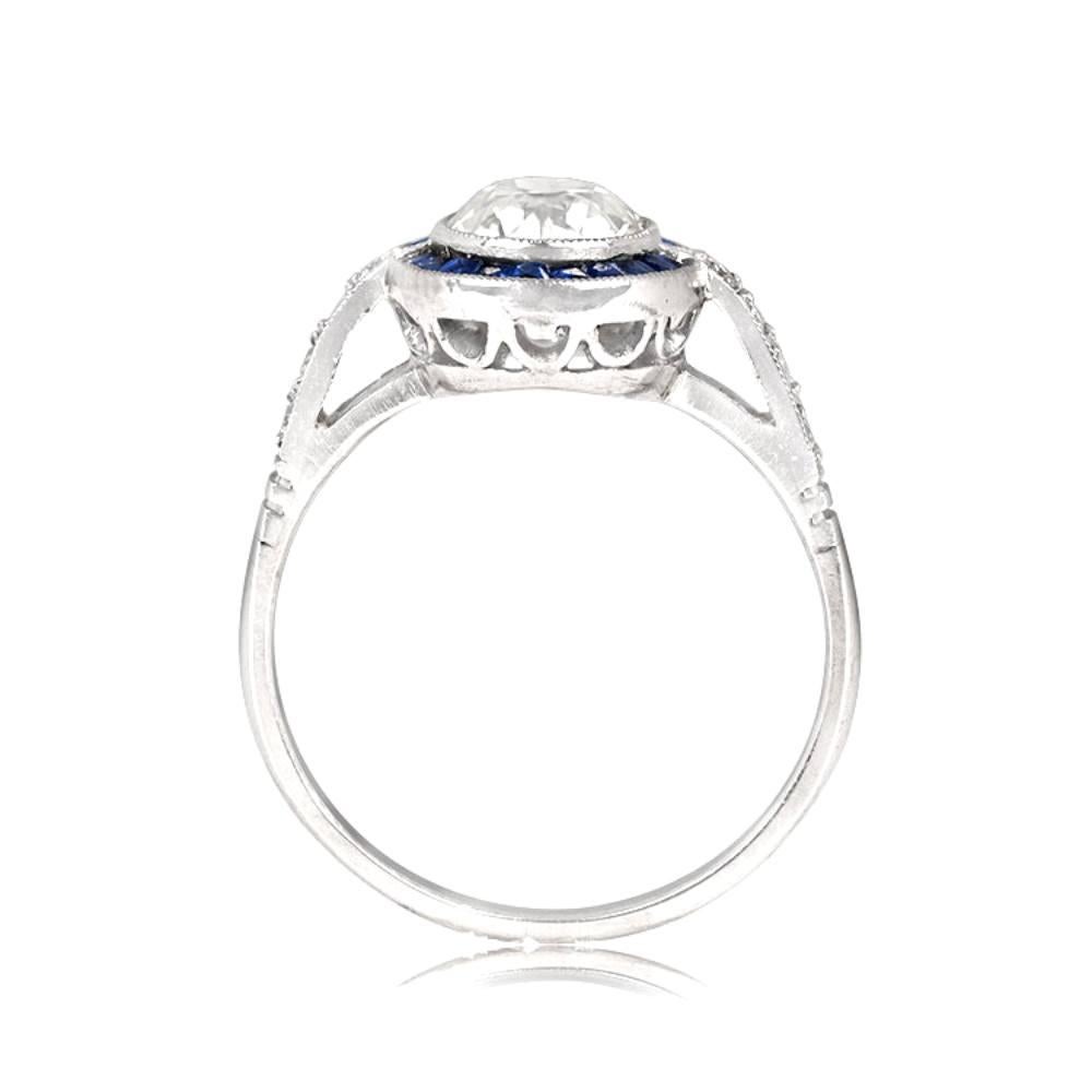 This exquisite platinum engagement ring showcases a 1.17-carat old European cut diamond, expertly bezel-set and encircled by a halo of precisely-cut French-cut sapphires. The J color and VS1 clarity of the center diamond are complemented by the rich