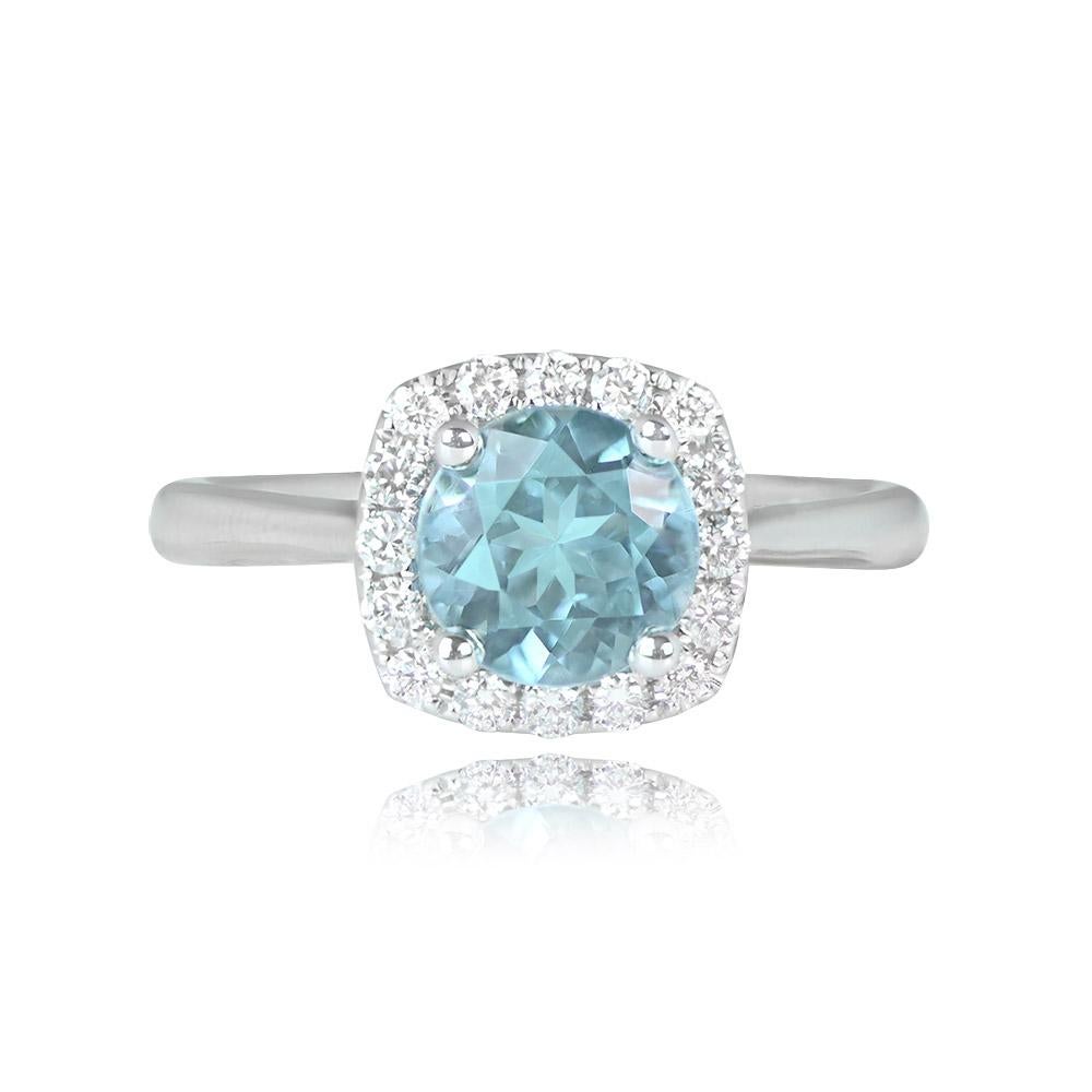 Captivating halo ring showcasing a vibrant 1.17-carat natural round aquamarine with strong saturation. The center aquamarine is surrounded by a cluster of micro-pave set round brilliant-cut diamonds, adding to its allure. Crafted in 18k white gold