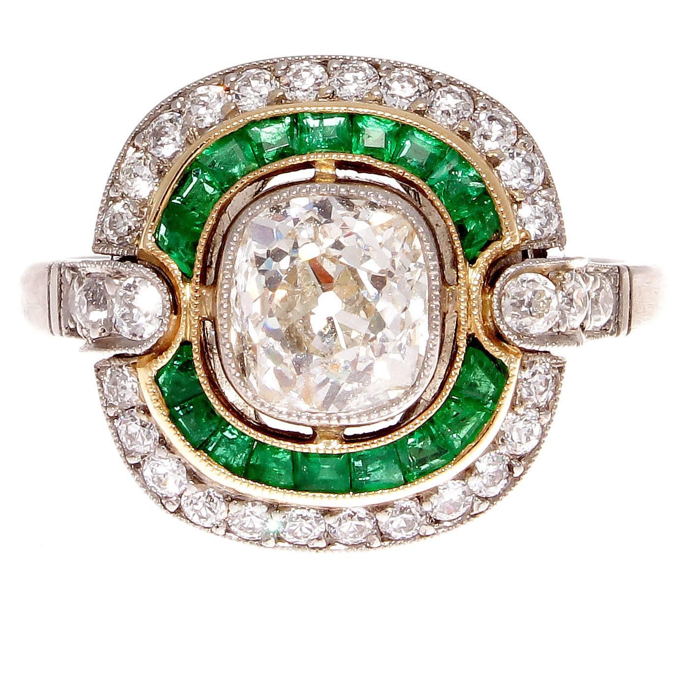 A double halo of intricacy and vibrant colors to create this vintage inspired engagement ring. Featuring a 1.18 carat old mine cut diamond that is J color, SI2 clarity surrounded by celestial circles of glowing forest green emeralds and numerous old