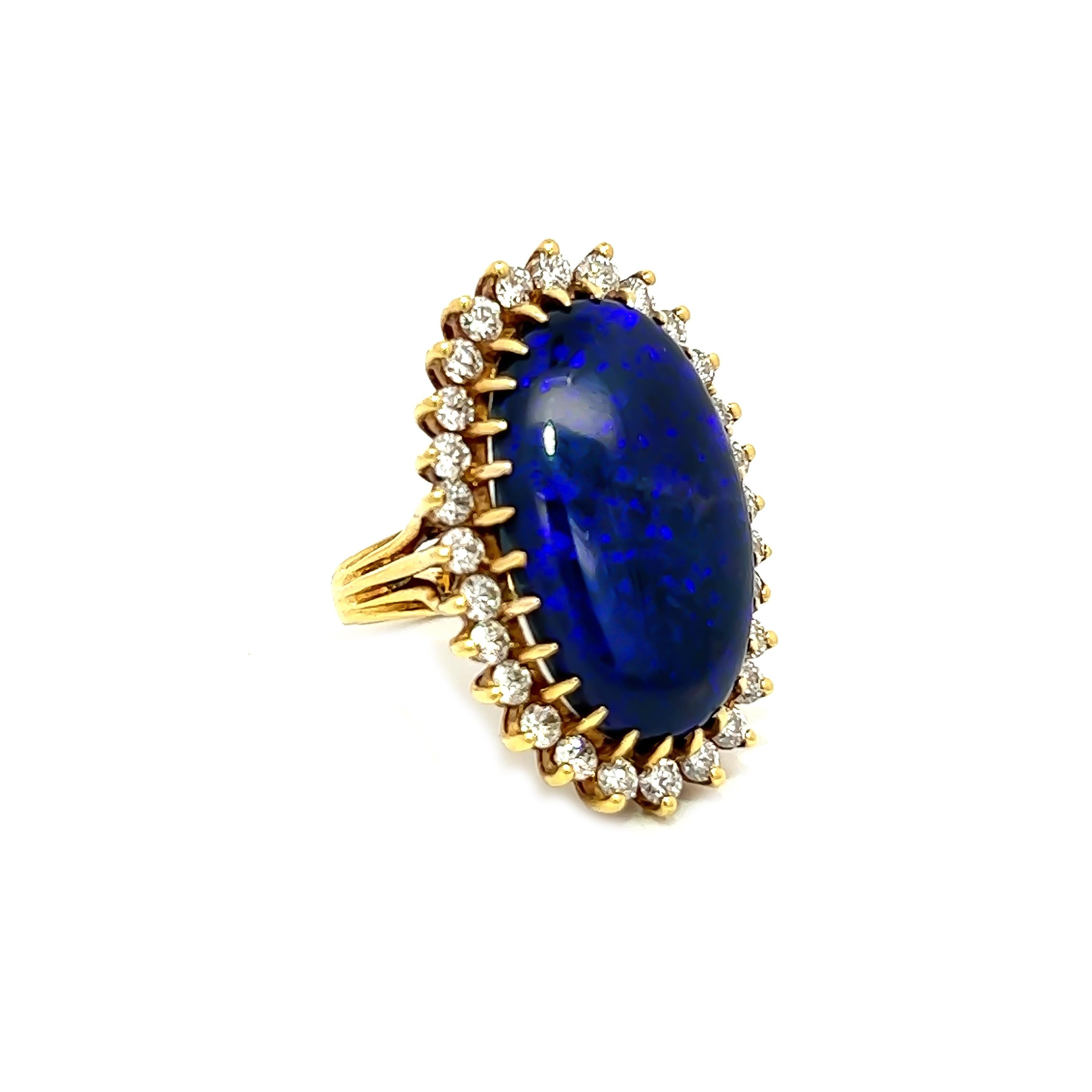 This exquisite black opal ring measures around 24x15MM and is an impressive 16.96CT in weight. The opal showcases a magnificent range of colors, with a captivating and deep purple hue being the most prominent. The opal is elegantly surrounded by 30