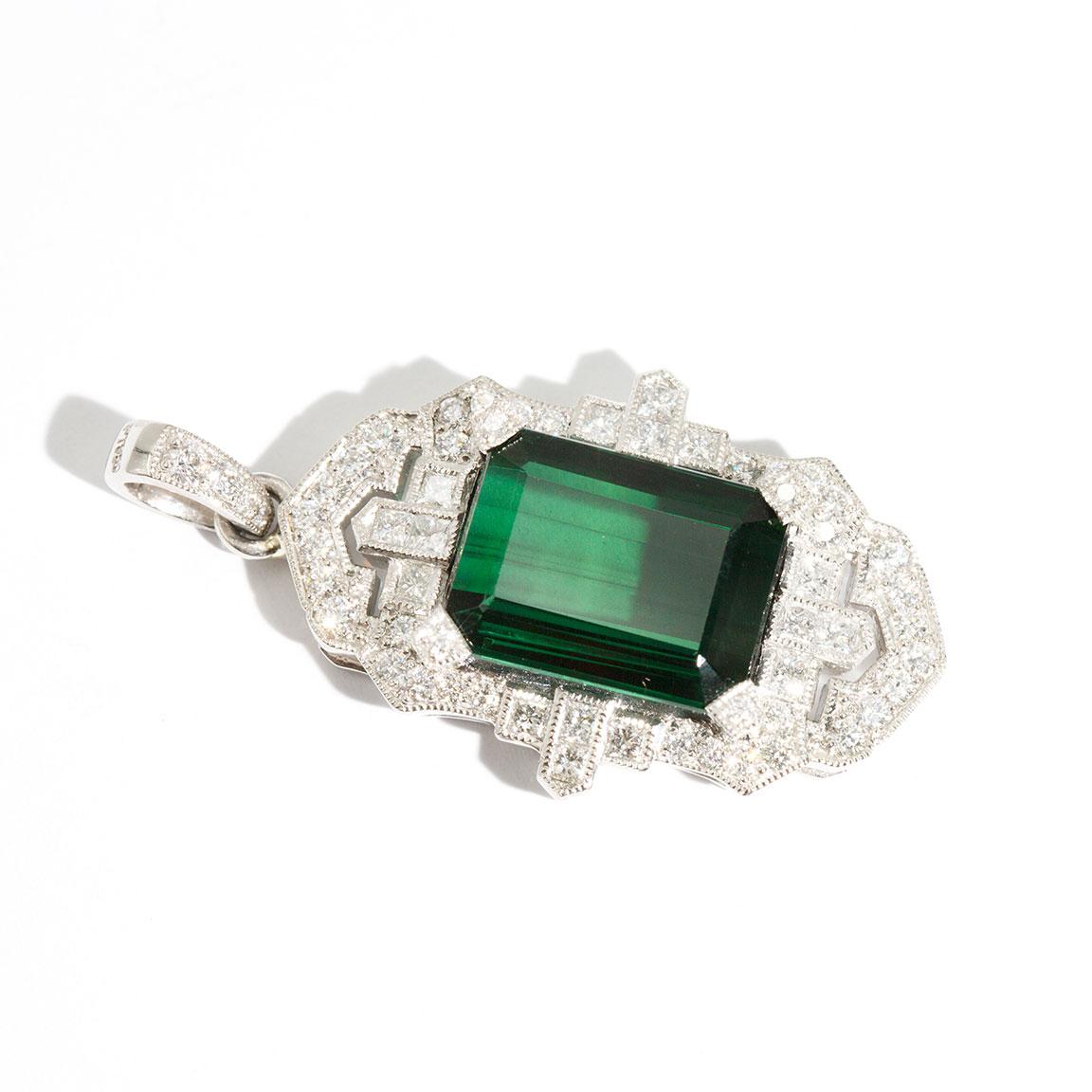Carefully crafted in platinum, this opulent Art Deco inspired pendant boasts a breathtaking flawless 11.84 carat modified emerald cut Tourmaline beset with an intricate border of round brilliant cut and princess cut diamonds totaling 1.40 carats. We