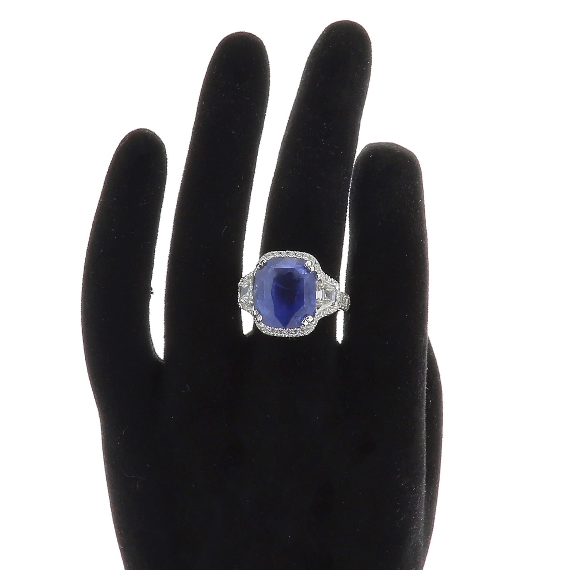 Ein erstaunlicher Cushion Ceylon Sapphire Ring:: flankiert auf jeder Seite von einem einzelnen trapezförmigen Diamanten und umgeben mit einem Halo von Diamanten mit einem Gewicht von 0::93 Karat. 
Das Gesamtgewicht des Ceylon-Saphirs beträgt 11::85