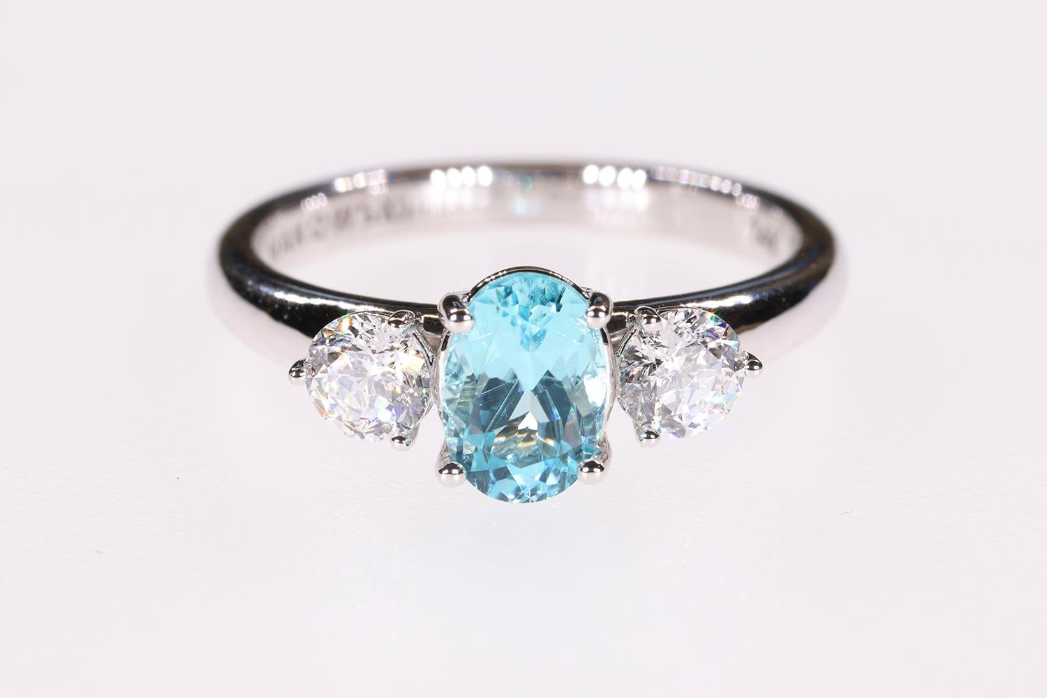 This is a beautiful Blue 1.19 Carat Paraiba Blue 3 Stone engagement ring that features two 88 faceted Sirius Star accent diamonds. The design is sleek and modern and cast in 14K white gold with a Bright Rhodium plating for extra brilliance and