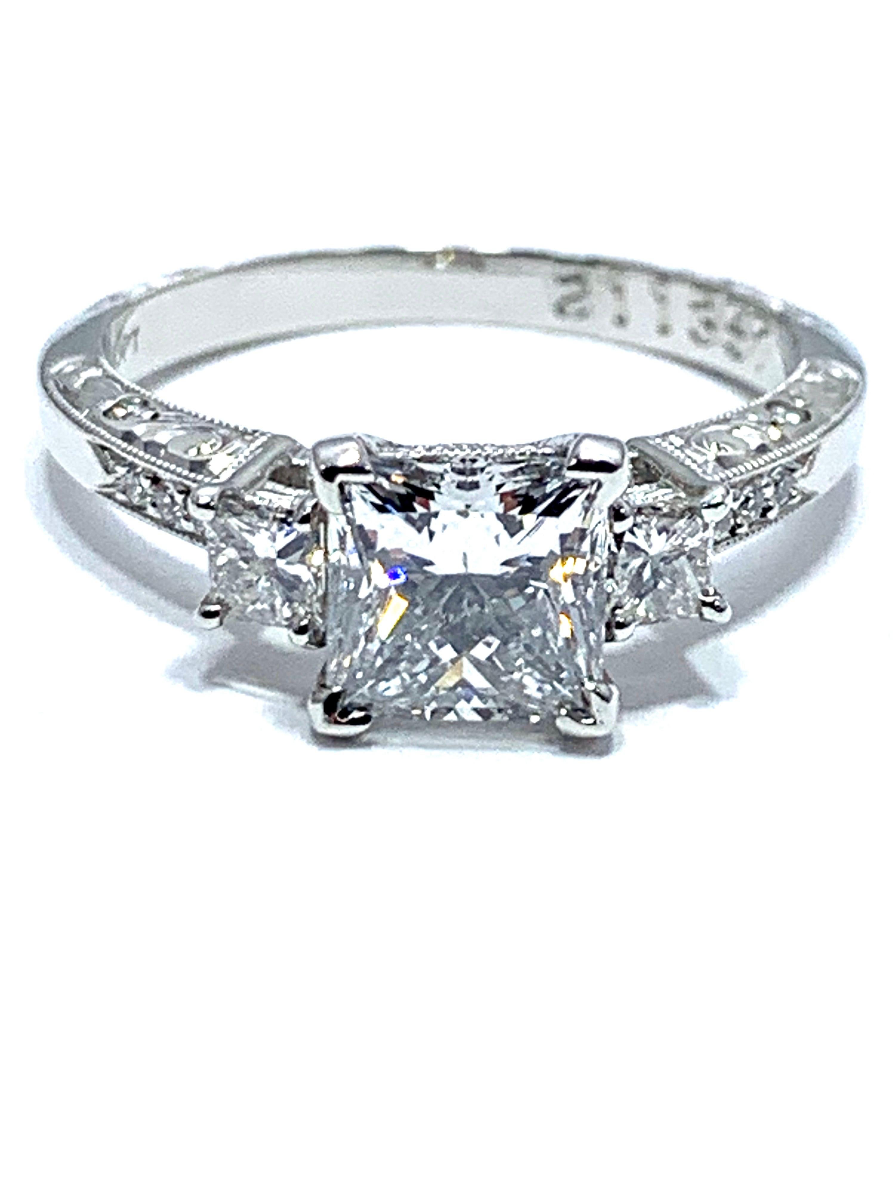 An eye catching 1.19 carat Princesscut brilliant diamond engagement ring.  The center diamond is set in a four prong platinum head with a single princess cut on either side and three round diamonds extending down the hand engraved  platinum shank.  