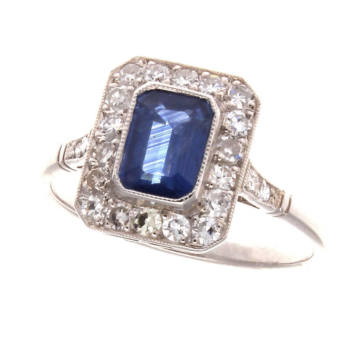 The halo ring was first introduced to the world during the Victorian era and the intentions were to emphasize the color of the center stone.  Featuring a 1.19 carat emerald cut serene blue sapphire that is perfectly framed by numerous colorless
