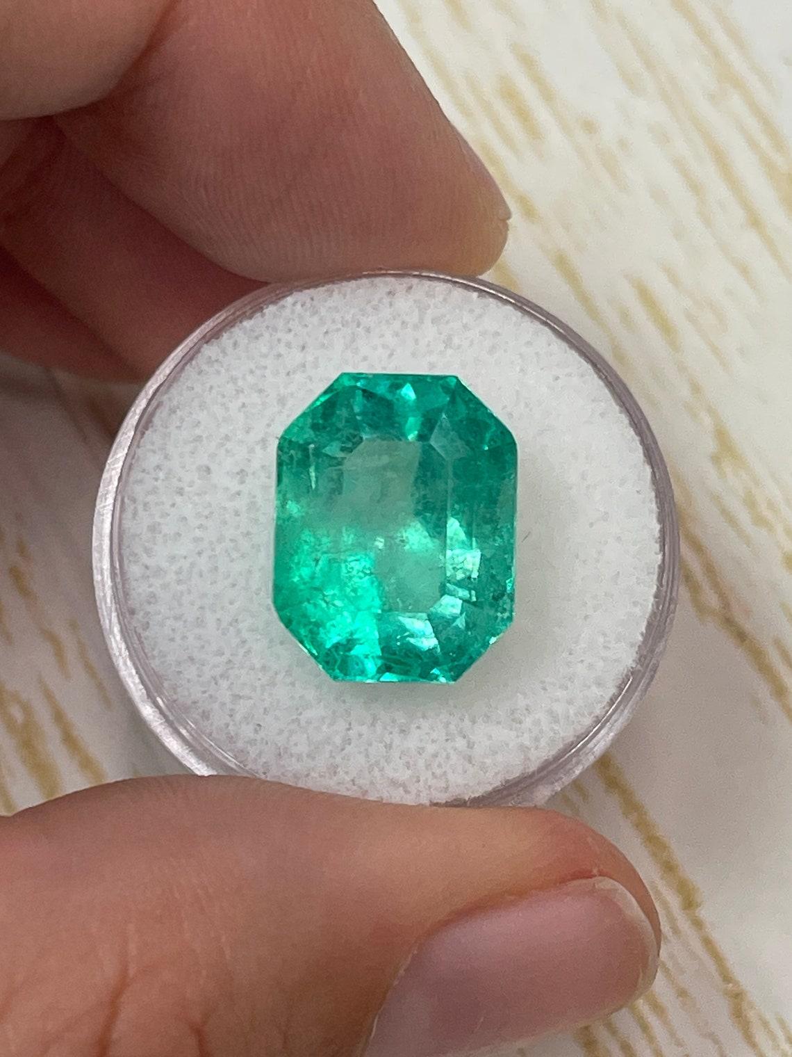 Stone: Emerald
Weight: 11.90-carats
Shape: Emerald Cut
Clarity: Transparent
Luster: Very Good
Color: Medium Green
Measurements: 14.92mm x 11.69mm x 10.58mm
Geographic Origin: Colombia
Treatment: Natural, Oiling

This emerald has surface-reaching