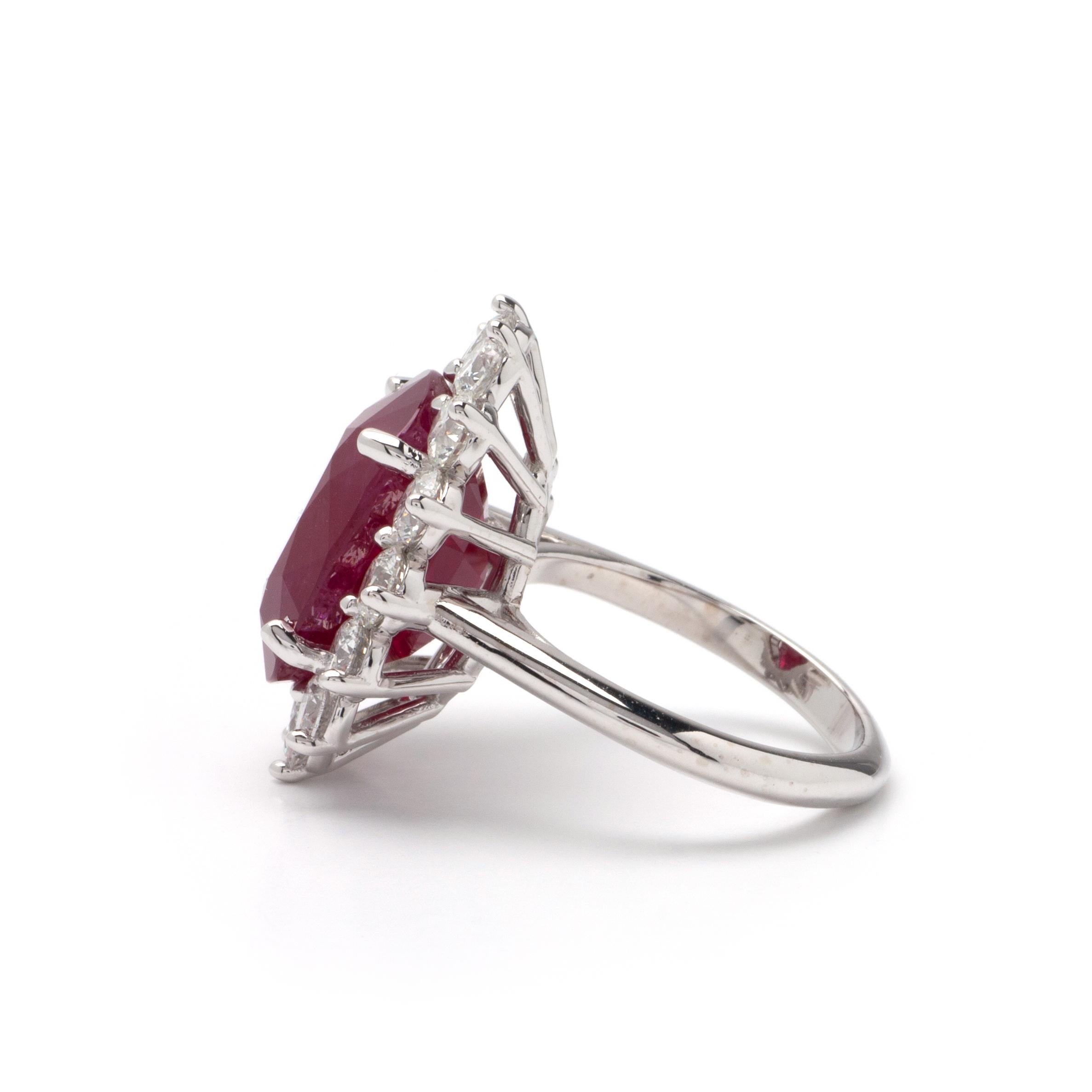 This ring features a halo design of G color, VS1 clarity, and 2.69ct Round side diamonds set in 14K white gold. The center gemstone is an 11.94ct oval ruby stone measuring 14.93 x 11.18 x 8.09mm. Finger size 6 1/4 with a free resizing.
