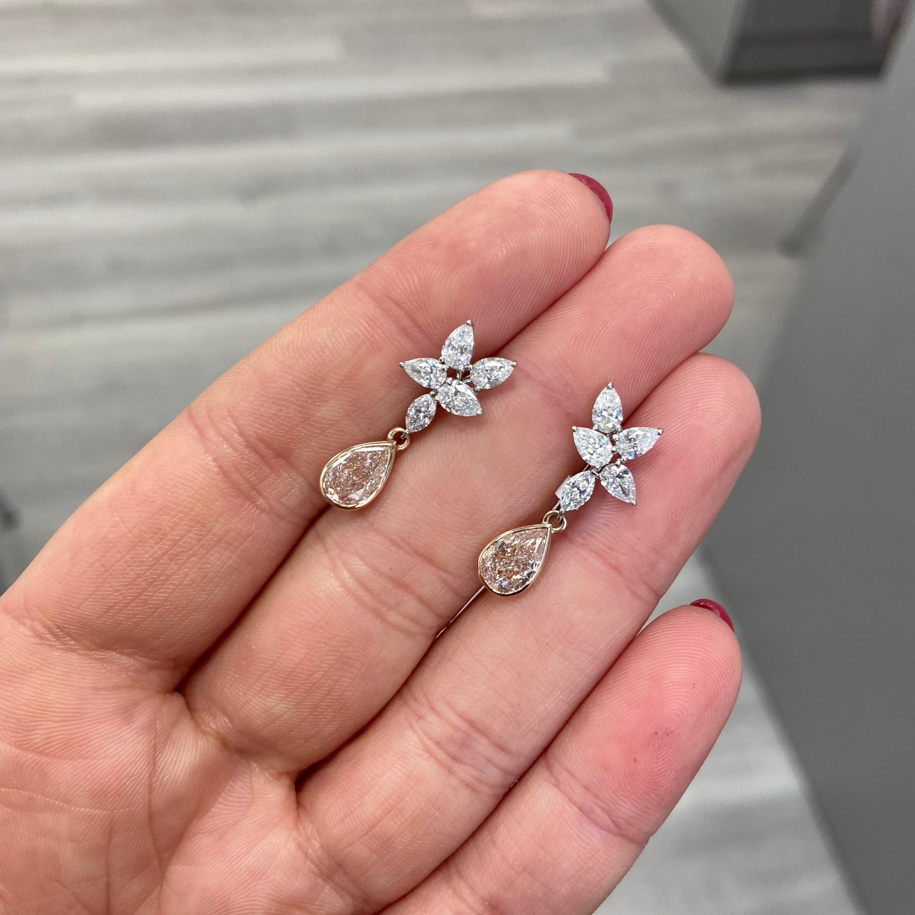 Sensational earrings with 1ct each GIA certified Fancy Light Brownish Pink Pear shapes set in a regal drop style with a cluster of colorless pear and marquise cut diamonds 
The pink pears are set in a rose gold bezel and face up with a pure pink