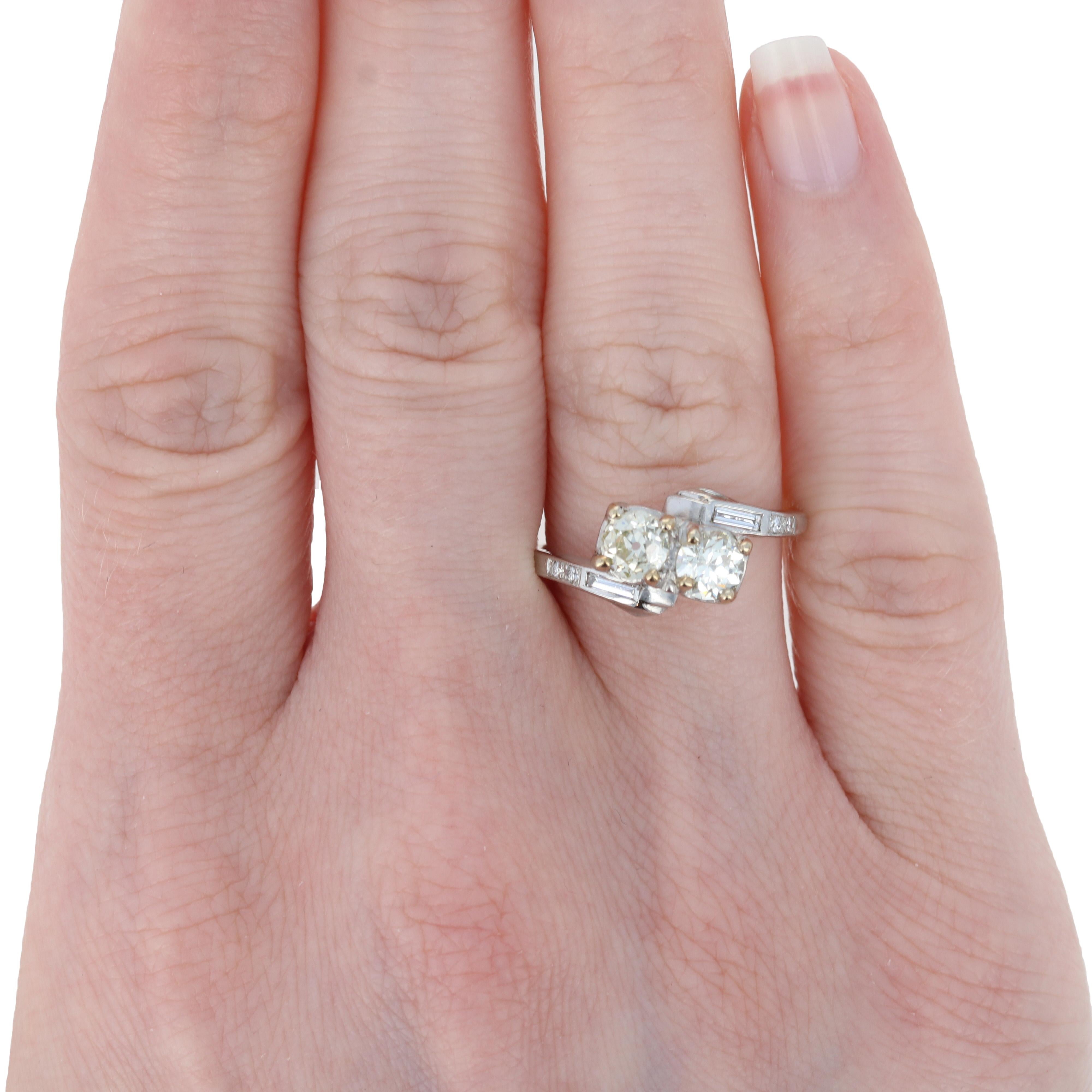 Propose in style with this gorgeous engagement ring! Fashioned in 14k white gold and palladium, a precious metal in the platinum family, this stunning piece features a bypass band adorned with natural diamonds. Two Old European cut diamonds take