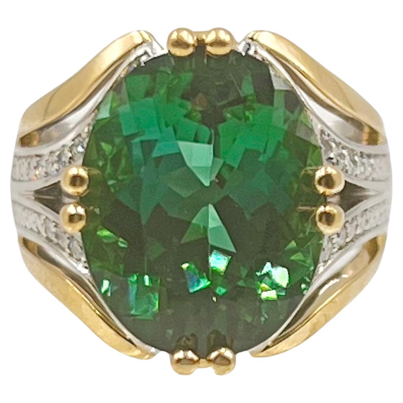 Green tourmaline ring by designer Coffin & Trout in platinum and 18k yellow gold.  Exquisite custom mounting set with a vibrant oval faceted green tourmaline weighing 11.12 carats. The top sides of the split design band are accented by forty-eight