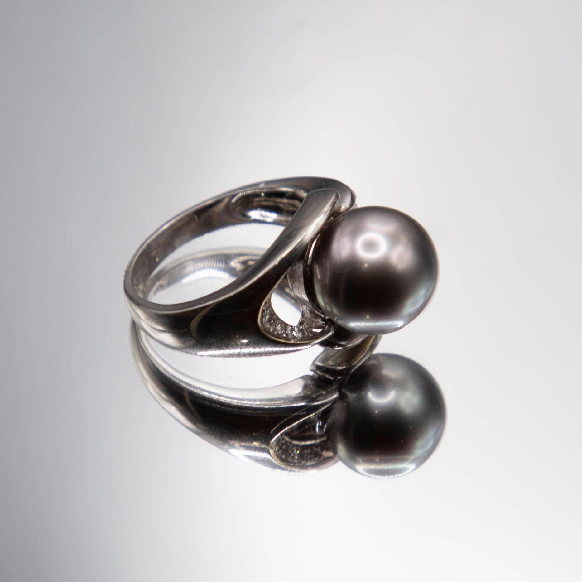 Classic contemporary defines this modified bypass  style 18k white gold ring featuring an important 11mm Tahitian Black South Sea pearl. The beautiful salt water gem displays excellent roundness, very high luster, thick nacre, near flawless