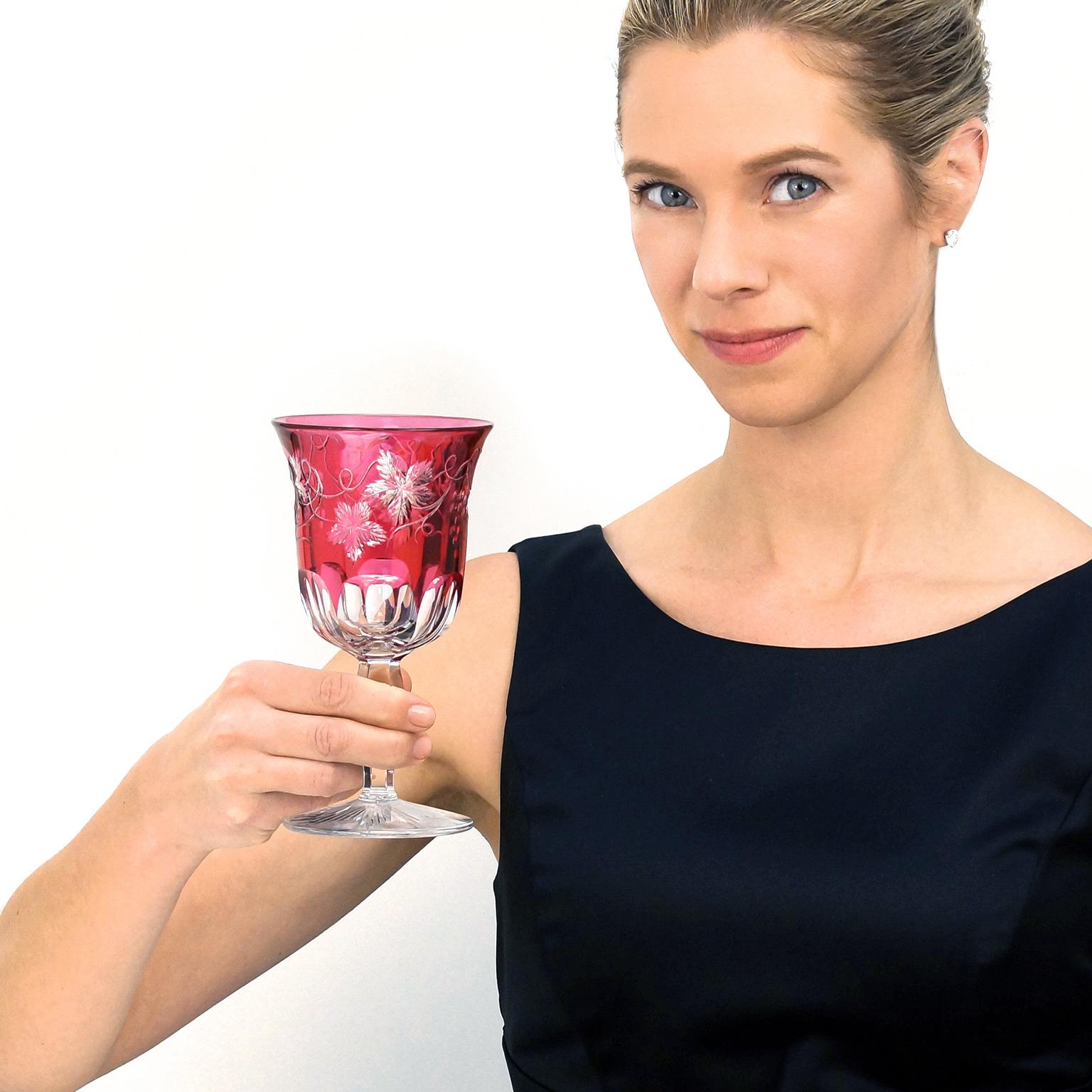 Circa 1925, American. These beautiful crystal water goblets in vibrant cranberry cut-to-clear feature an intricate grapevine pattern complete with swirling tendrils and detailed leaves. Comfortable in the hand, they are meticulously made and in