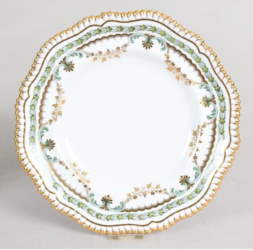 An elegant set of dinner plates by the re known English firm Spode and custom ordered through the fine Gilded Age Retailer Davis Collamore New York. These feature a shaped gadroon edge and two lovely colors of green intertwined on their collars.