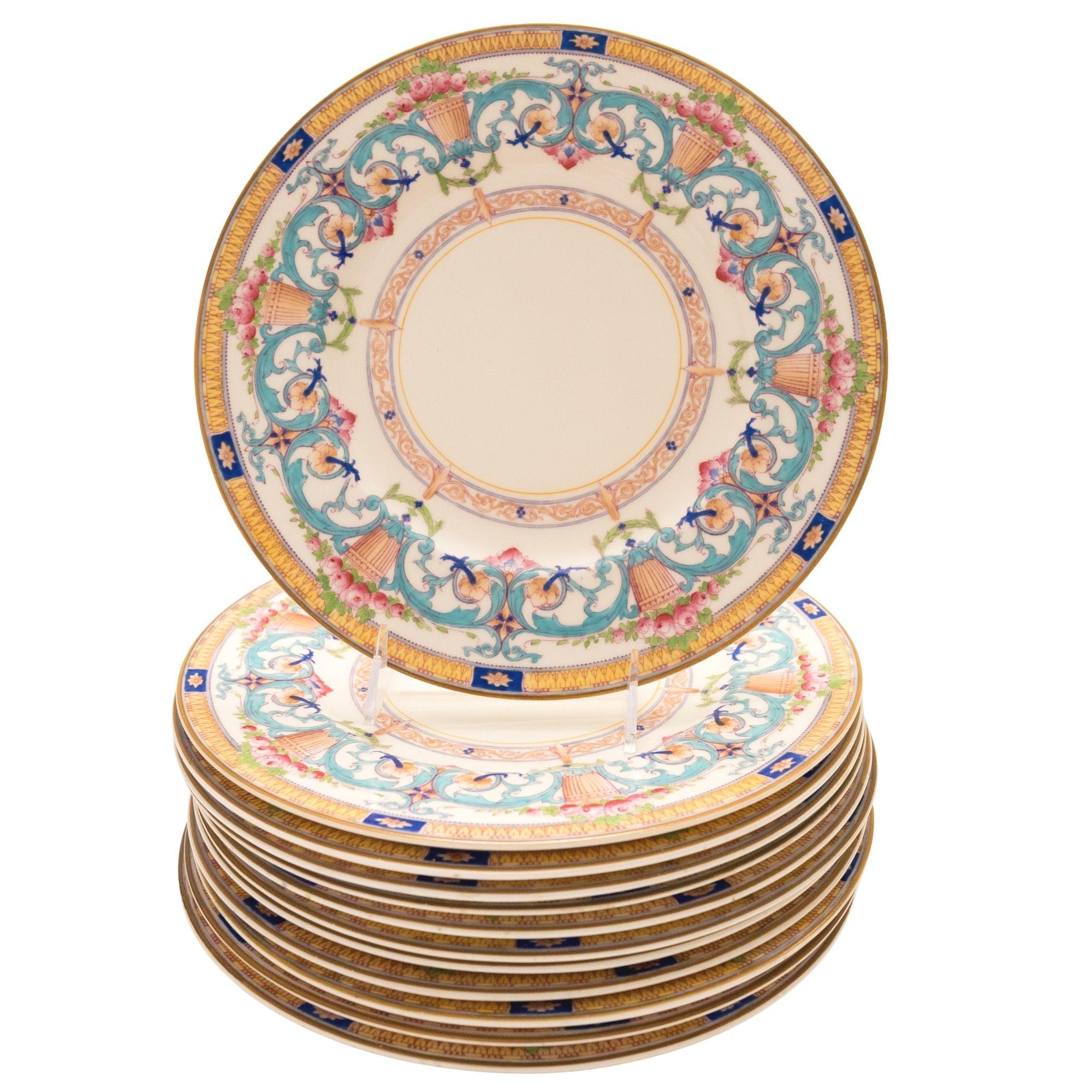 A colorful and elaborately hand enameled set of 12 dinner plates by one of England's most re known firm: Royal Worcester. This set features turquoise, pink, cobalt, greens and yellows in a pretty floral basket swag design. In really nice antique