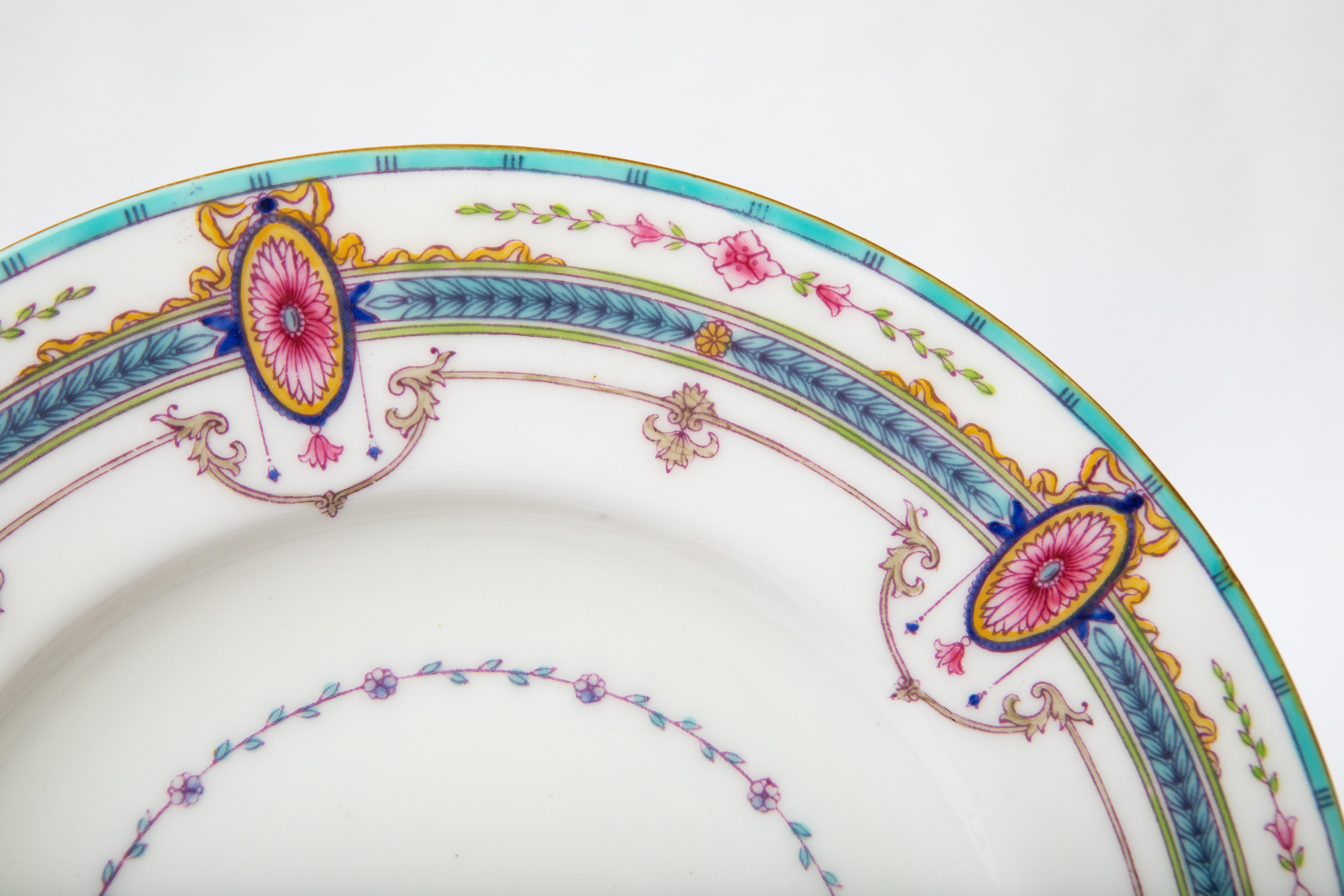 A pretty set of antique English bone china plates with an attractive color palette of pink and turquoise featuring an oval cartouche with bow surround. Custom ordered through the fine Gilded Age Retailer Spaulding & Co Chicago. They are all in very