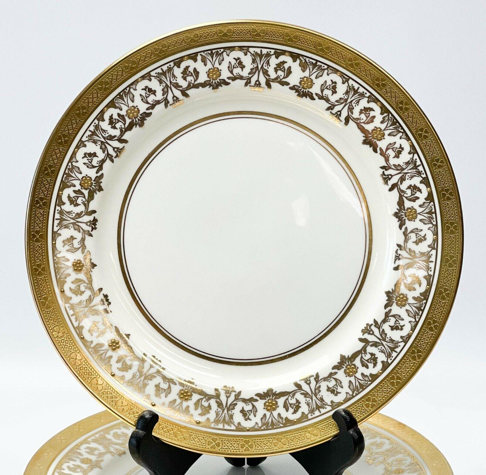 12 Aynsley England Porcelain dessert plates in Kenilworth ivory, circa 1940

A white center with an off-white ground to the edge with ornate gilt foliate decoration with raised gold floral accents. A geometric floral pattern to the gilt rims.