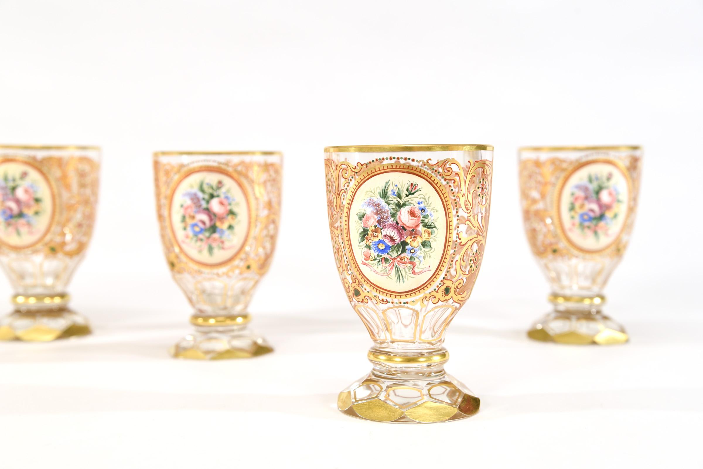 A rare and elegant set of 12 Bohemian ( and possibly Russian) hand blown tumblers with facet cut base and gilt trim. Each piece is decorated with hand painted floral reserves in polychrome enamels and further decorated in gold around the