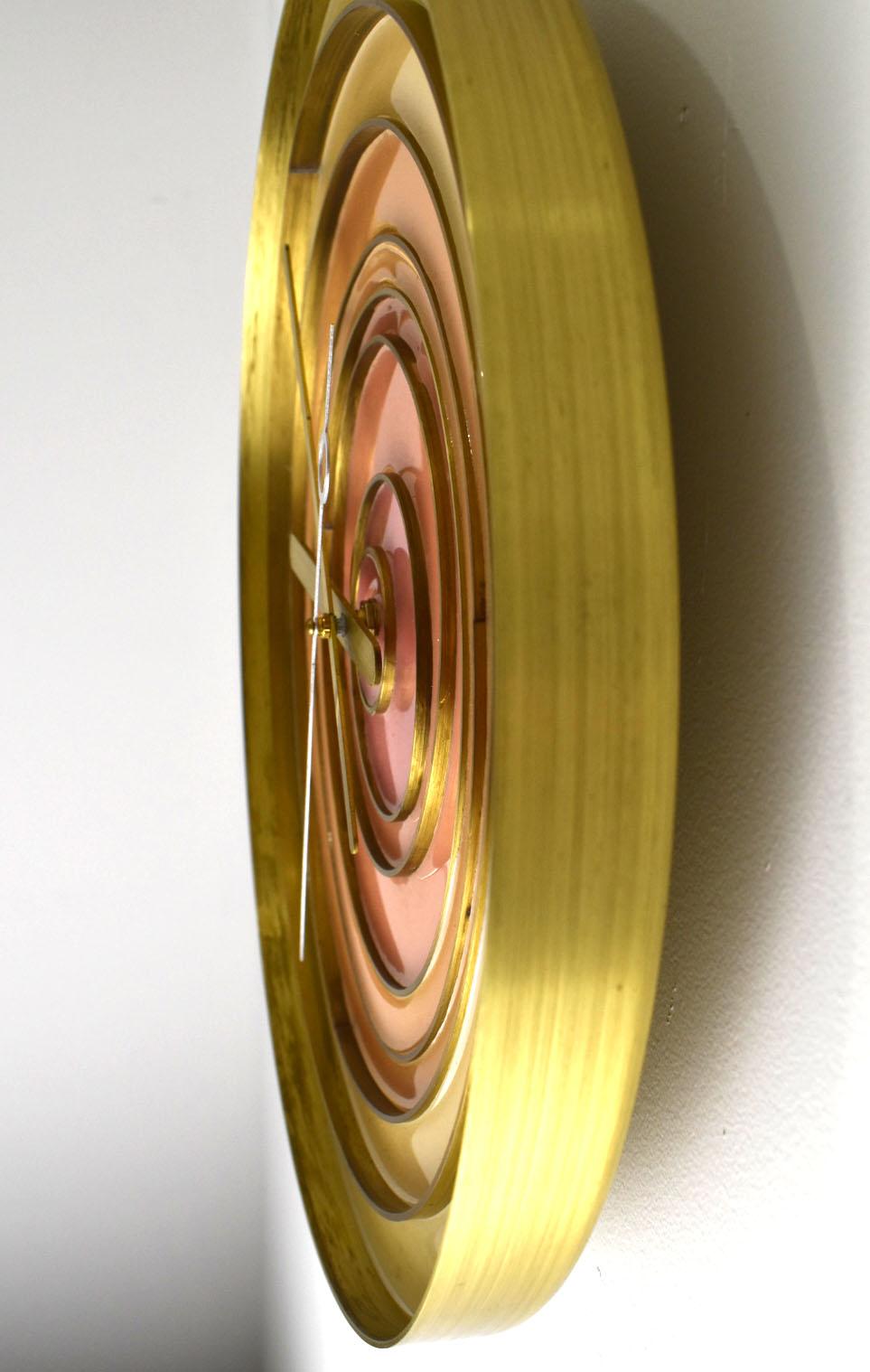 This stunning clock is made of a single spun piece of solid brass.  It is  designed with inlaid varying sized brass rings and then filled with tinted epoxy poured.   The hour and minute hands are hand cut, a continuous sweep hand mechanism has been