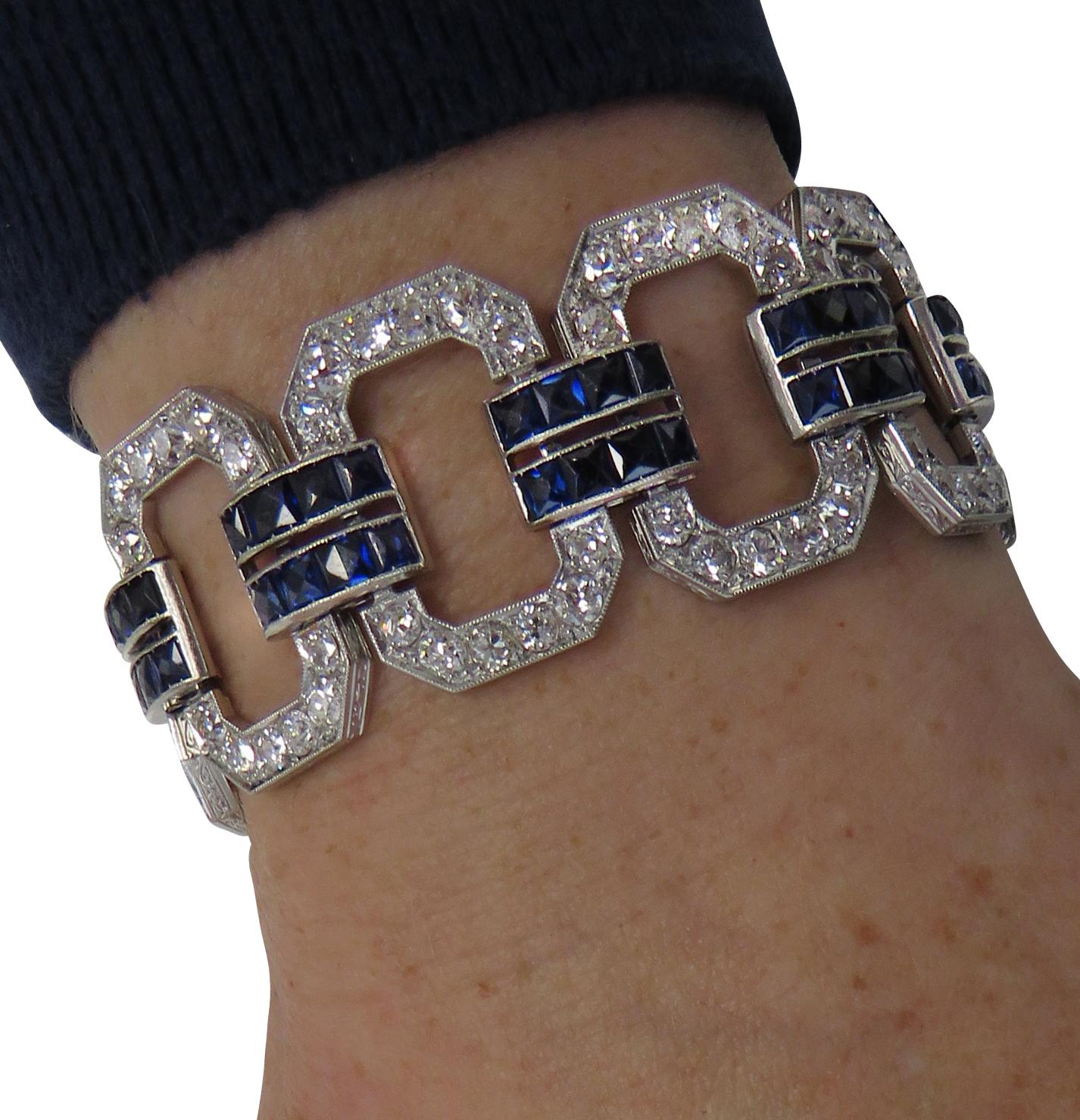 Stunning Art Deco bracelet crafted in platinum featuring old European cut diamonds weighing approximately 12 carat total, G-H color, VS-SI clarity adorned with square cut synthetic sapphires. Diamond encrusted open metal work links are tied together